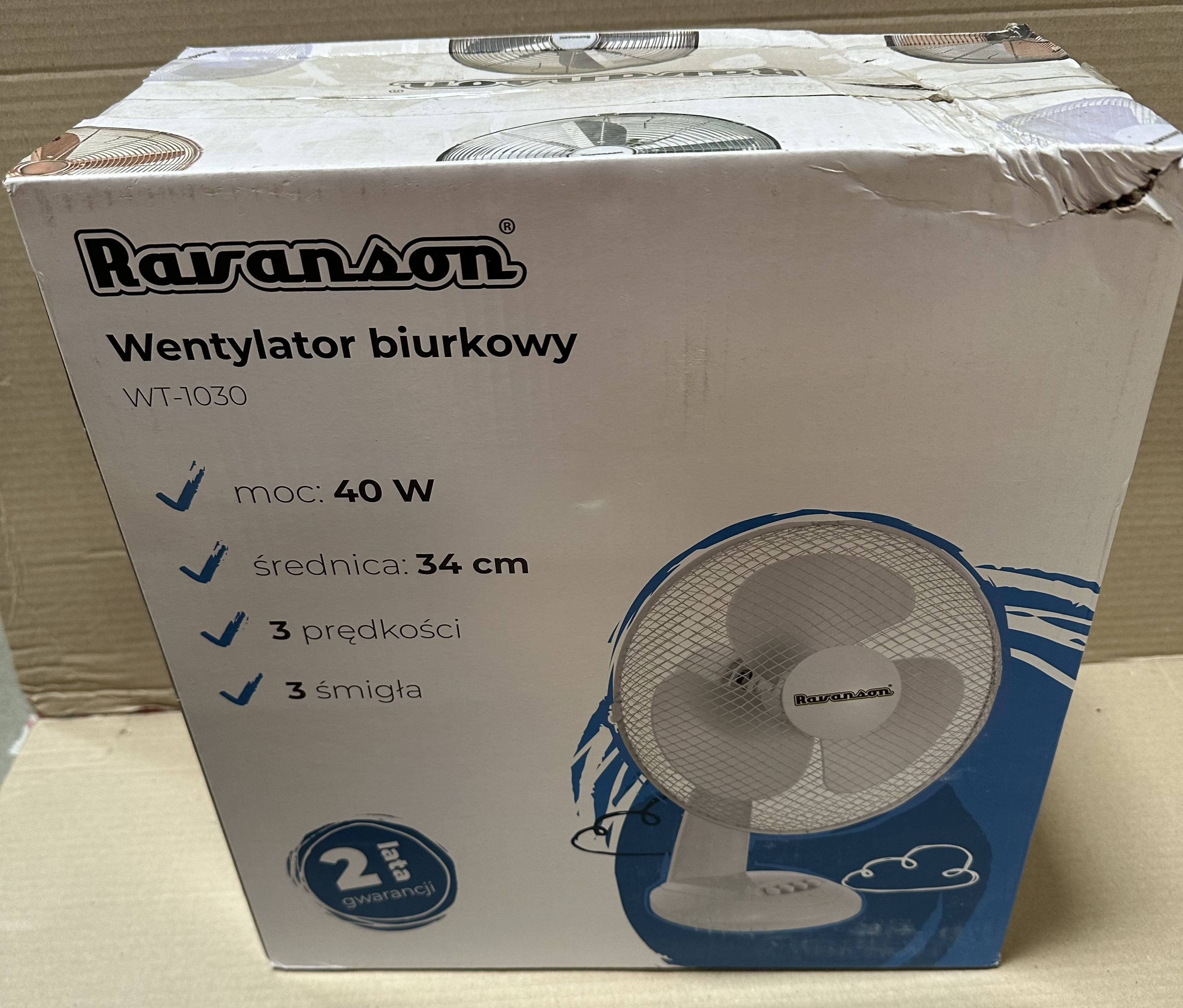 Pudełko kartonowe z białym wentylatorem biurkowym w środku i polskim tekstem.