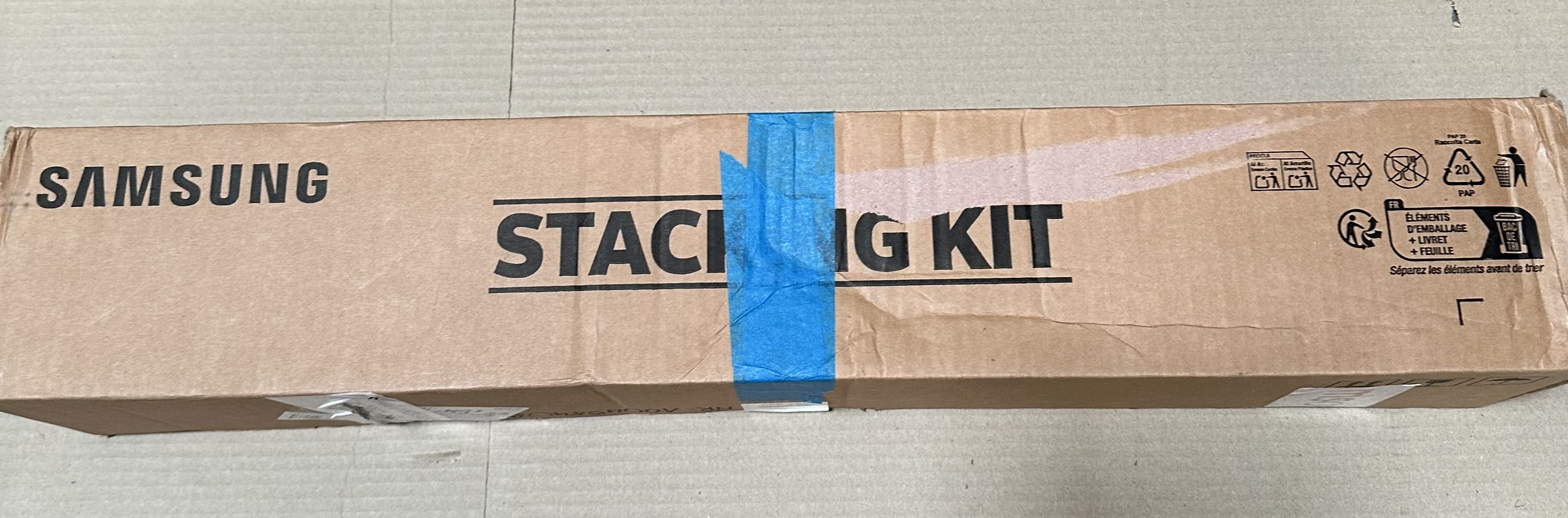 Pudełko kartonowe Samsung Stacking Kit z niebieską taśmą i symbolami recyklingu.