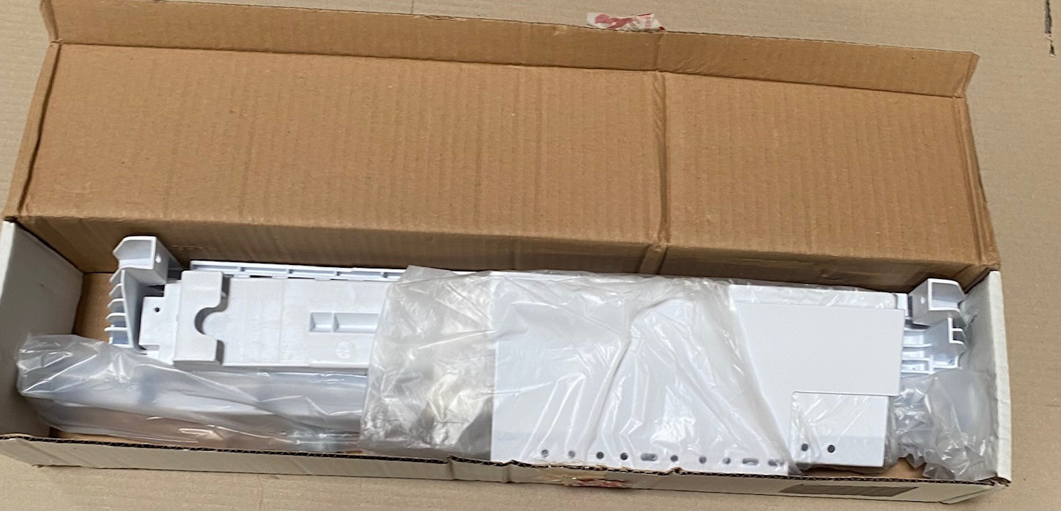 Otwarty karton zawierający białe elementy owinięte w plastik.