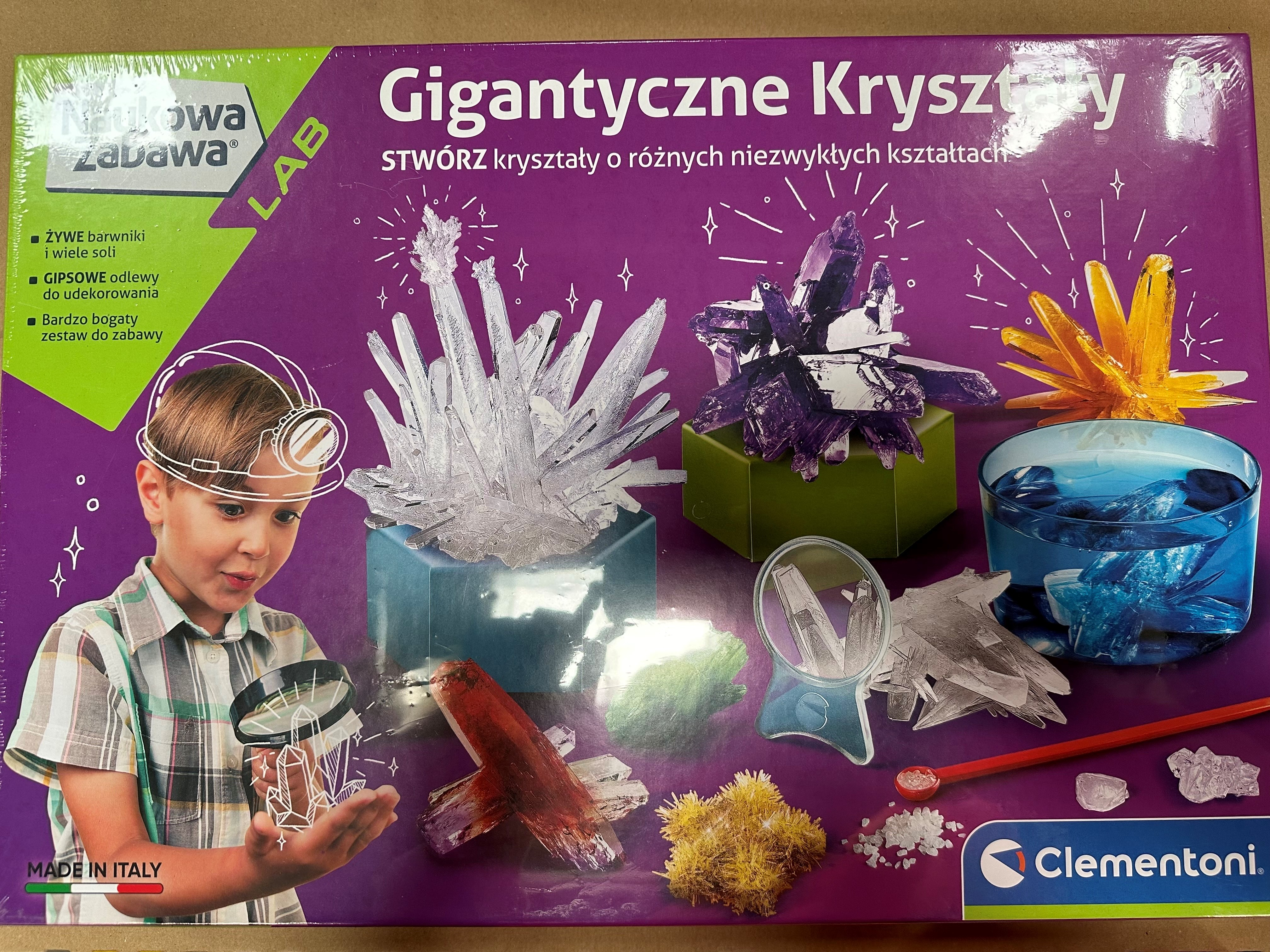 Chłopiec bada zestaw do hodowli kryształów. Pudełko pokazuje kryształy i dziecko z lupą.