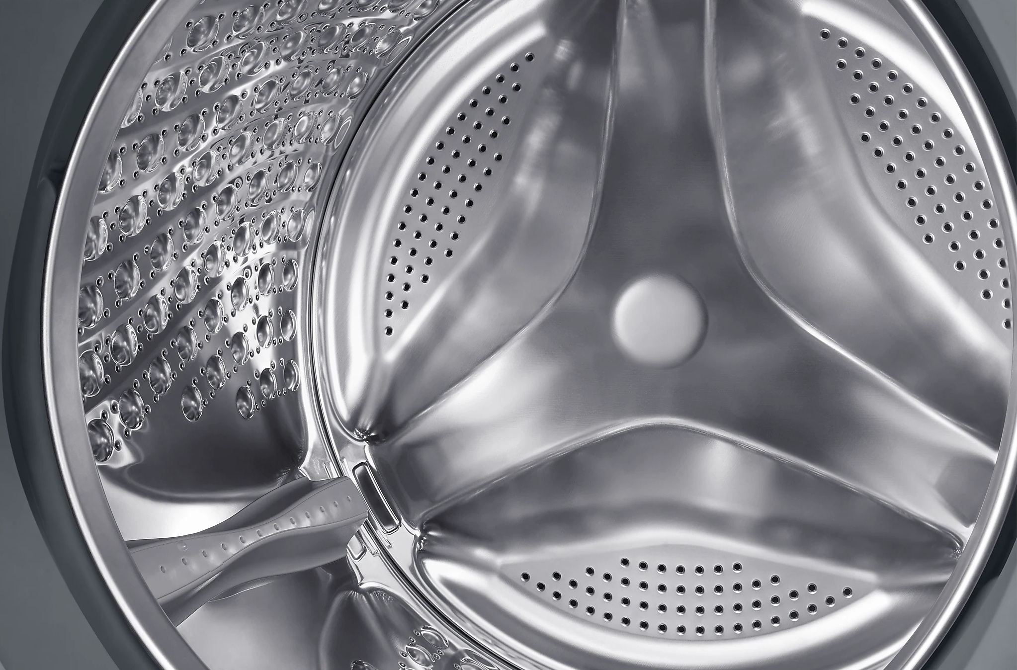 Zbliżenie wnętrza bębna pralki. Stal nierdzewna.