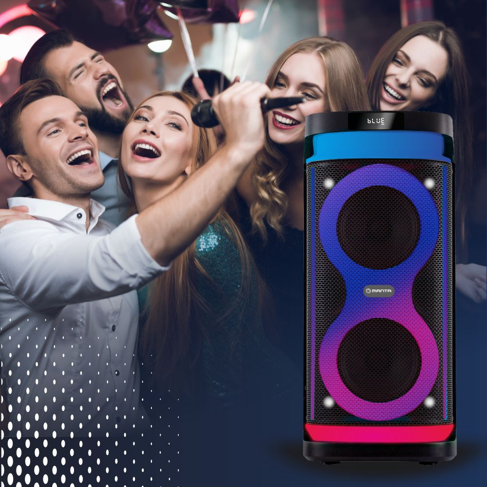 Grupa osób śpiewa z maszyną do karaoke i dużym głośnikiem ze zmieniającymi się kolorami.