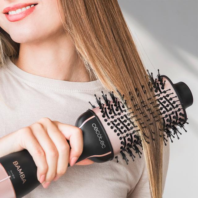 Kobieta używa szczotki do suszenia włosów, stylizując swoje blond włosy.