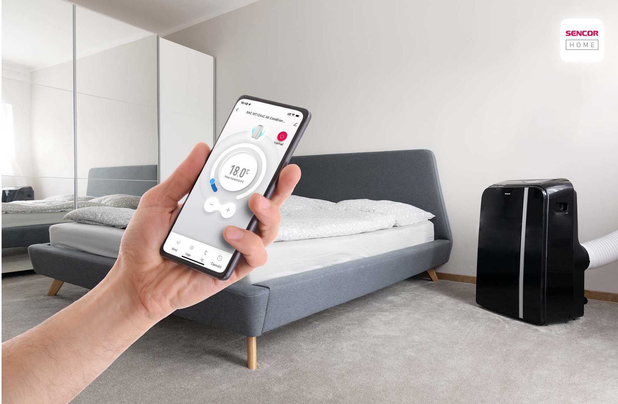 Osoba trzymająca smartfon z aplikacją klimatyzacji, w sypialni.