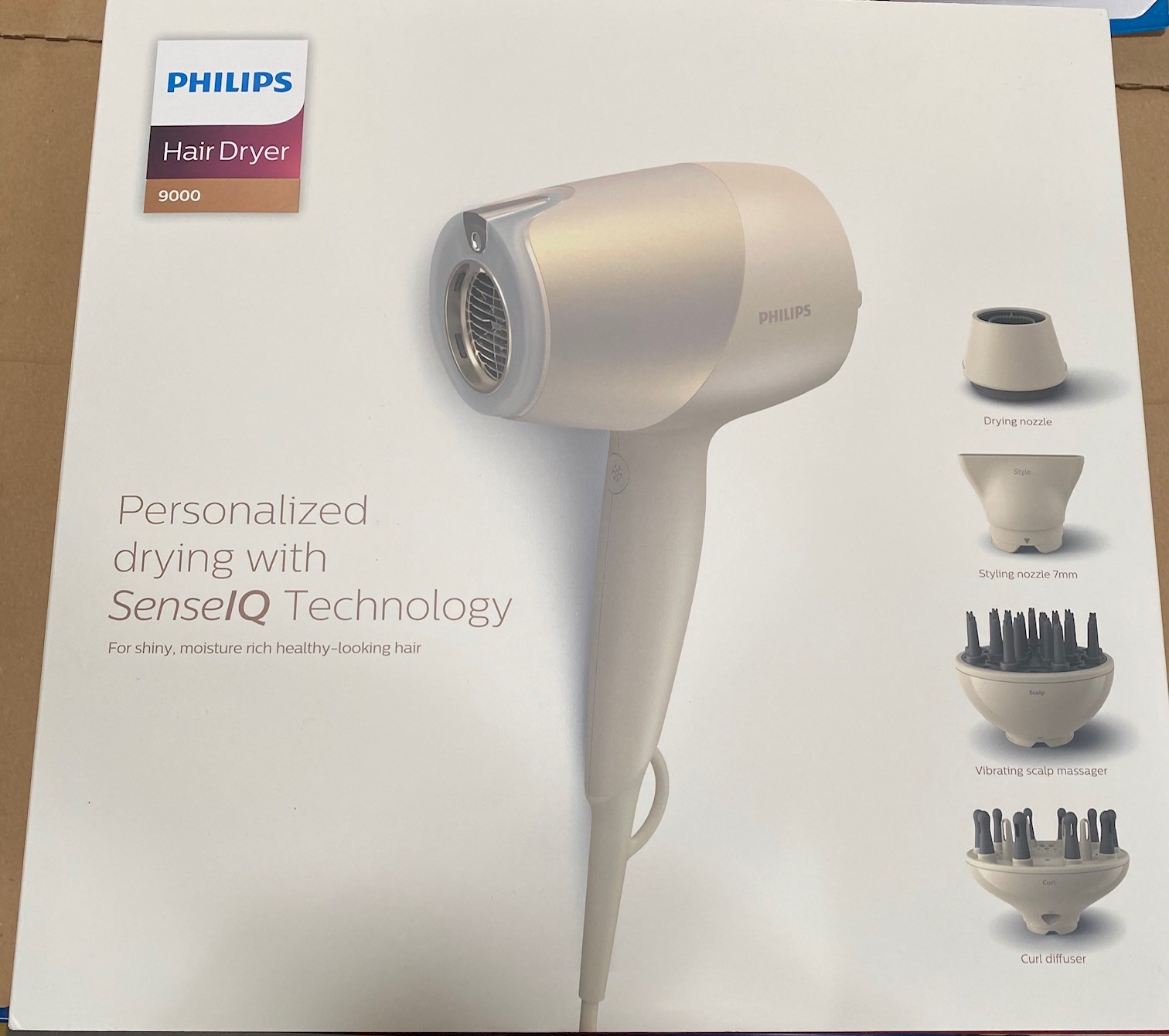 Biała suszarka do włosów z akcesoriami w pudełku z napisem "PHILIPS".