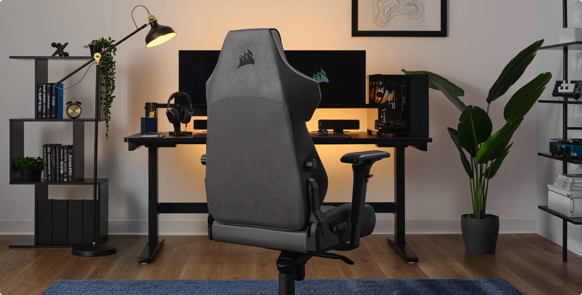 Krzesło do gier w domowym biurze. Czarne biurko z komputerem i akcesoriami. Półka na książki i lampa.