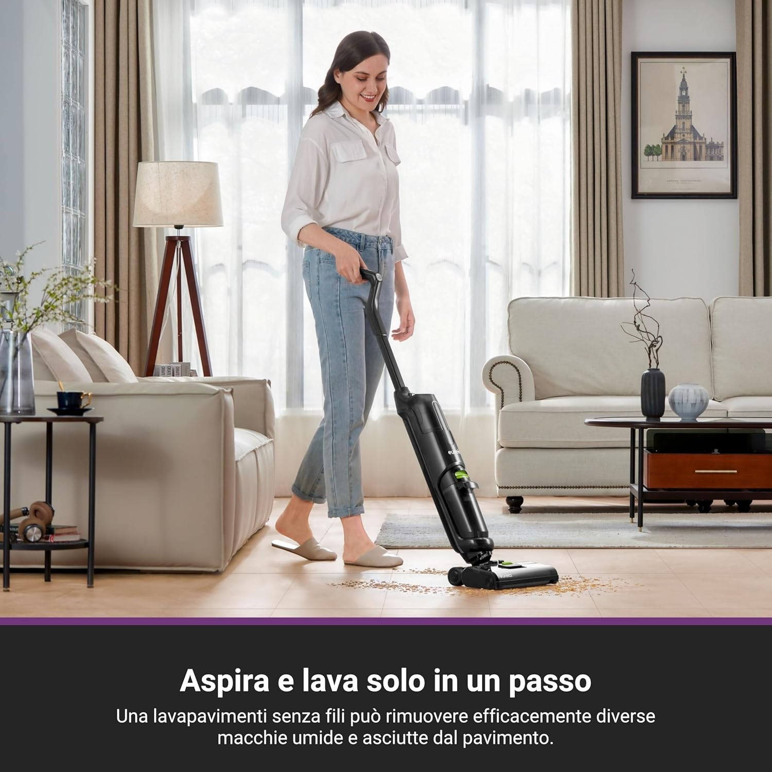 Donna che usa un aspirapolvere a bastone nero. Sta aspirando un pavimento. Divano beige e mobili in legno.