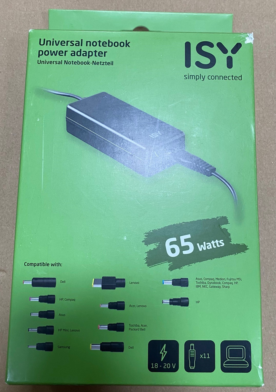 Zielone pudełko z zasilaczem do laptopa. Widoczny tekst i różne typy złączy.