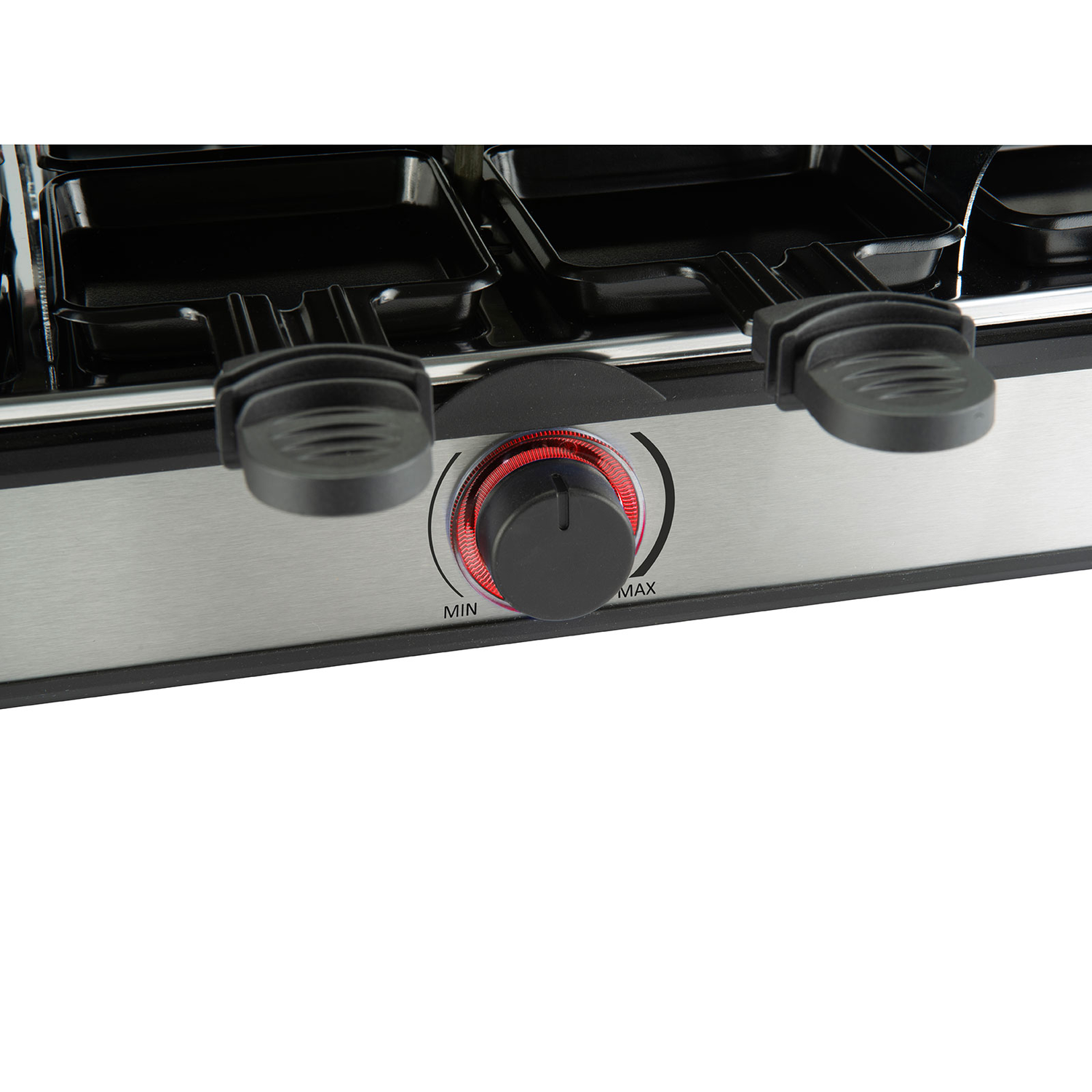 Close-up van een raclette grill. Het heeft zwarte bakjes, een zilveren basis en een knop met rode accenten.
