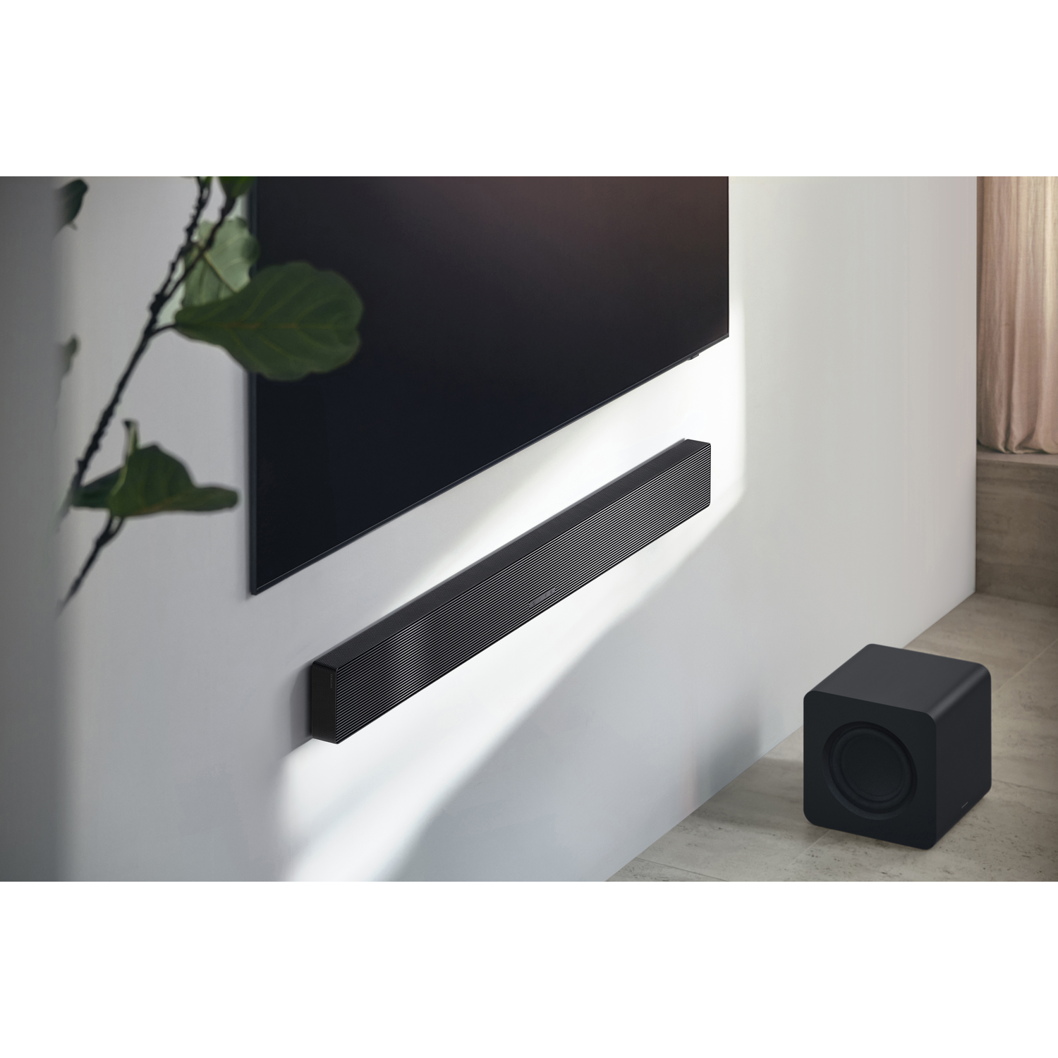 Soundbar mounted on a wall with a black TV above. A subwoofer sits below.