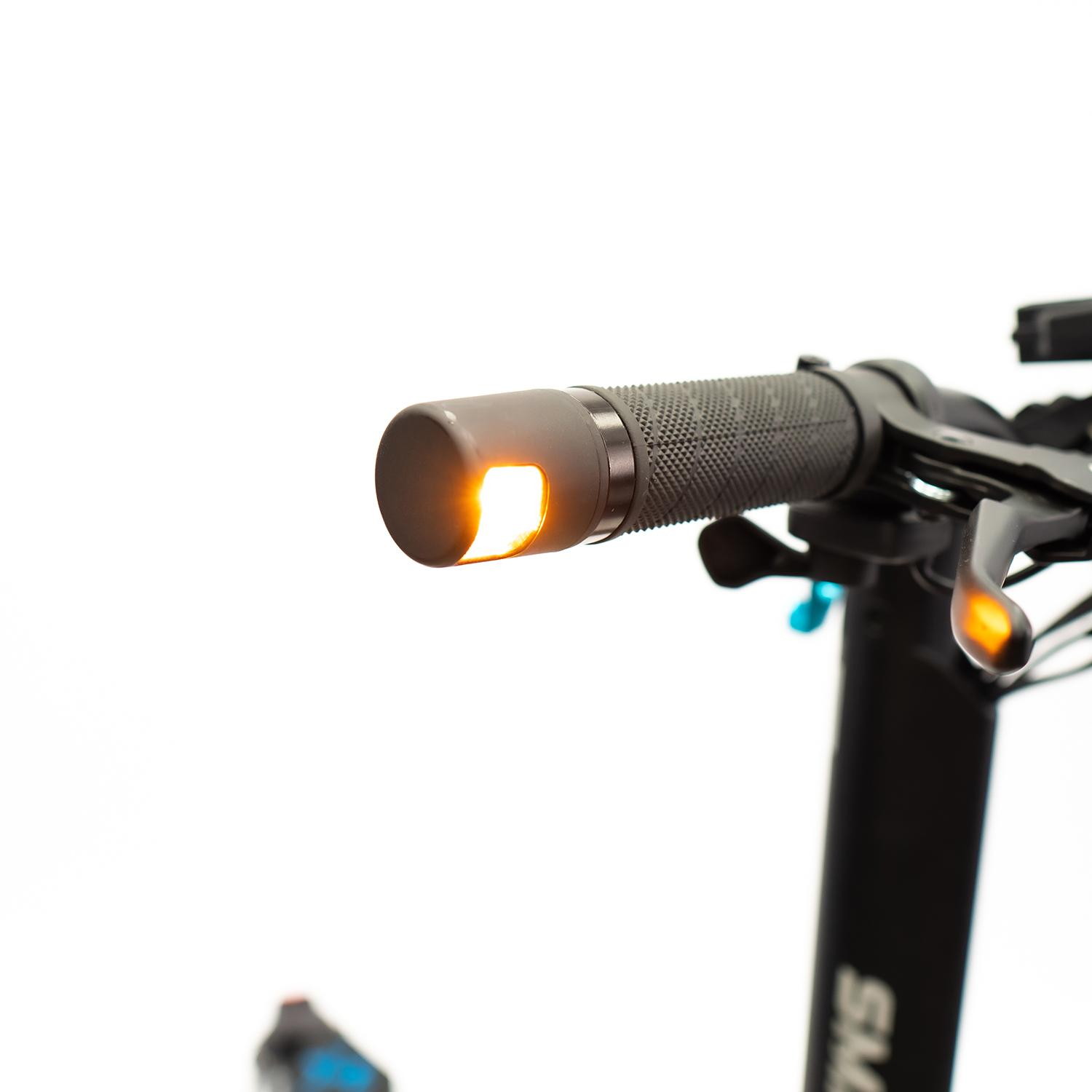 Primer plano del manillar de un scooter con una luz de señal naranja encendida.