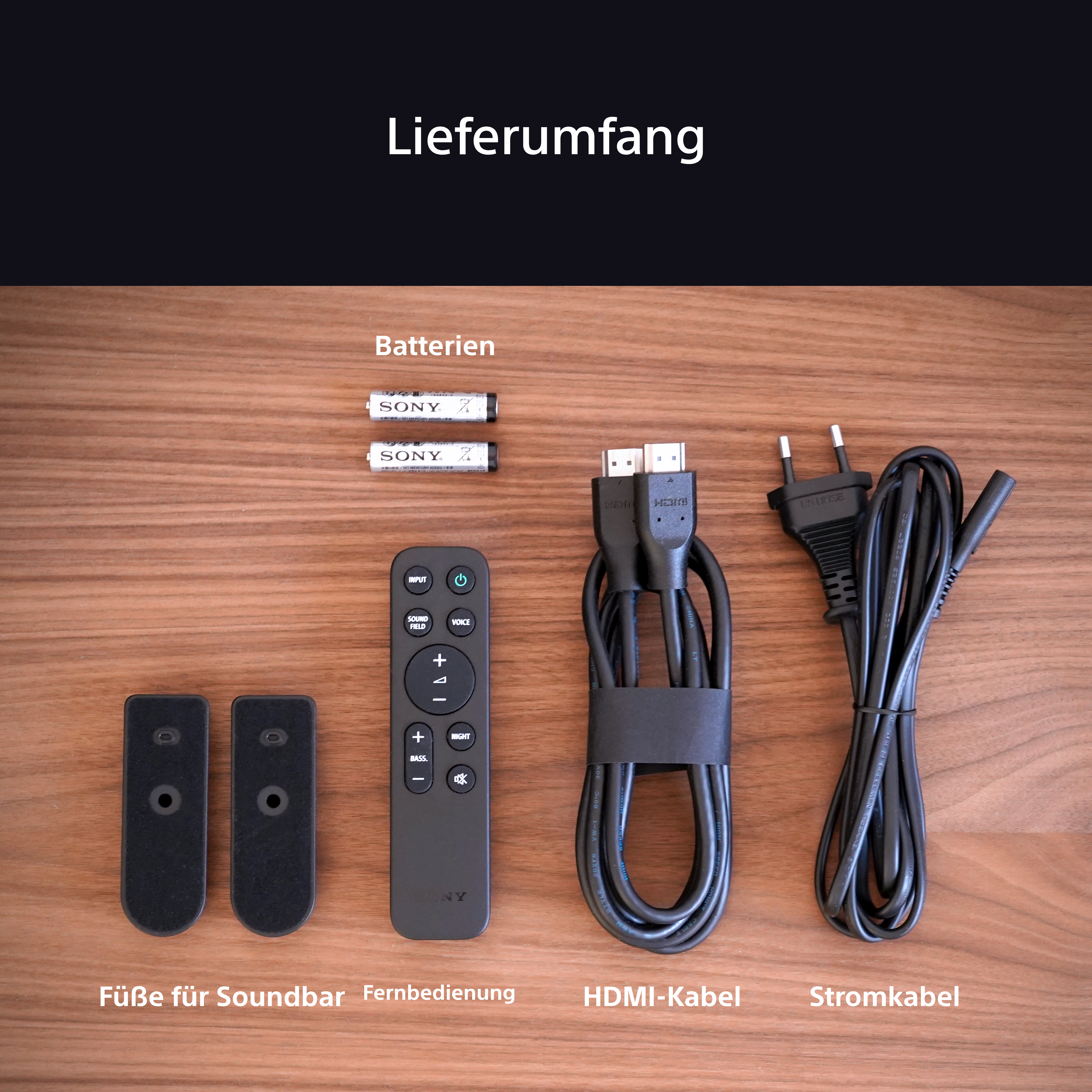 Das Bild zeigt Komponenten einer Soundbar: Fernbedienung, Kabel und Füße.