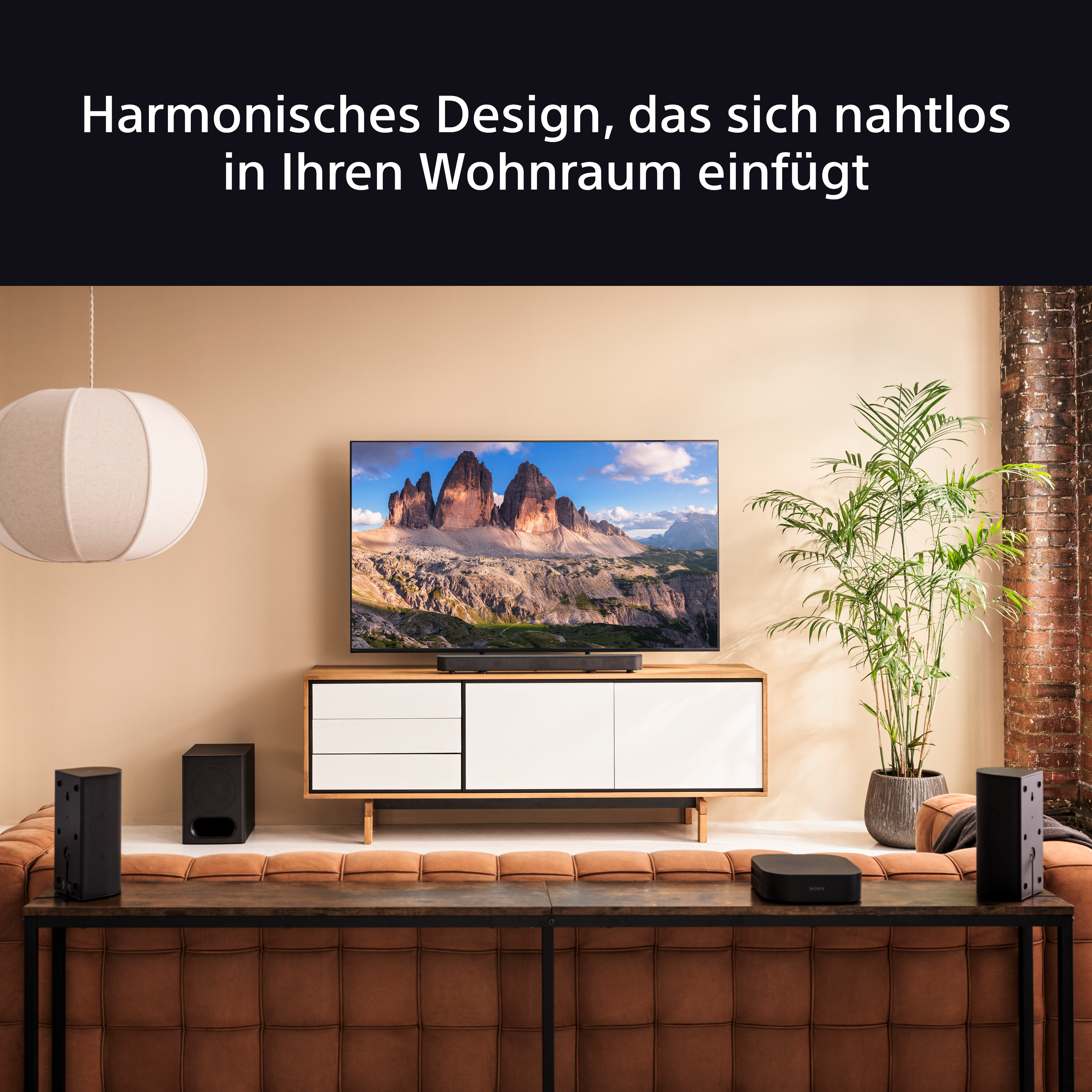 Wohnzimmer mit TV, Holzschrank, Lautsprechern, Sofa und Pflanze.