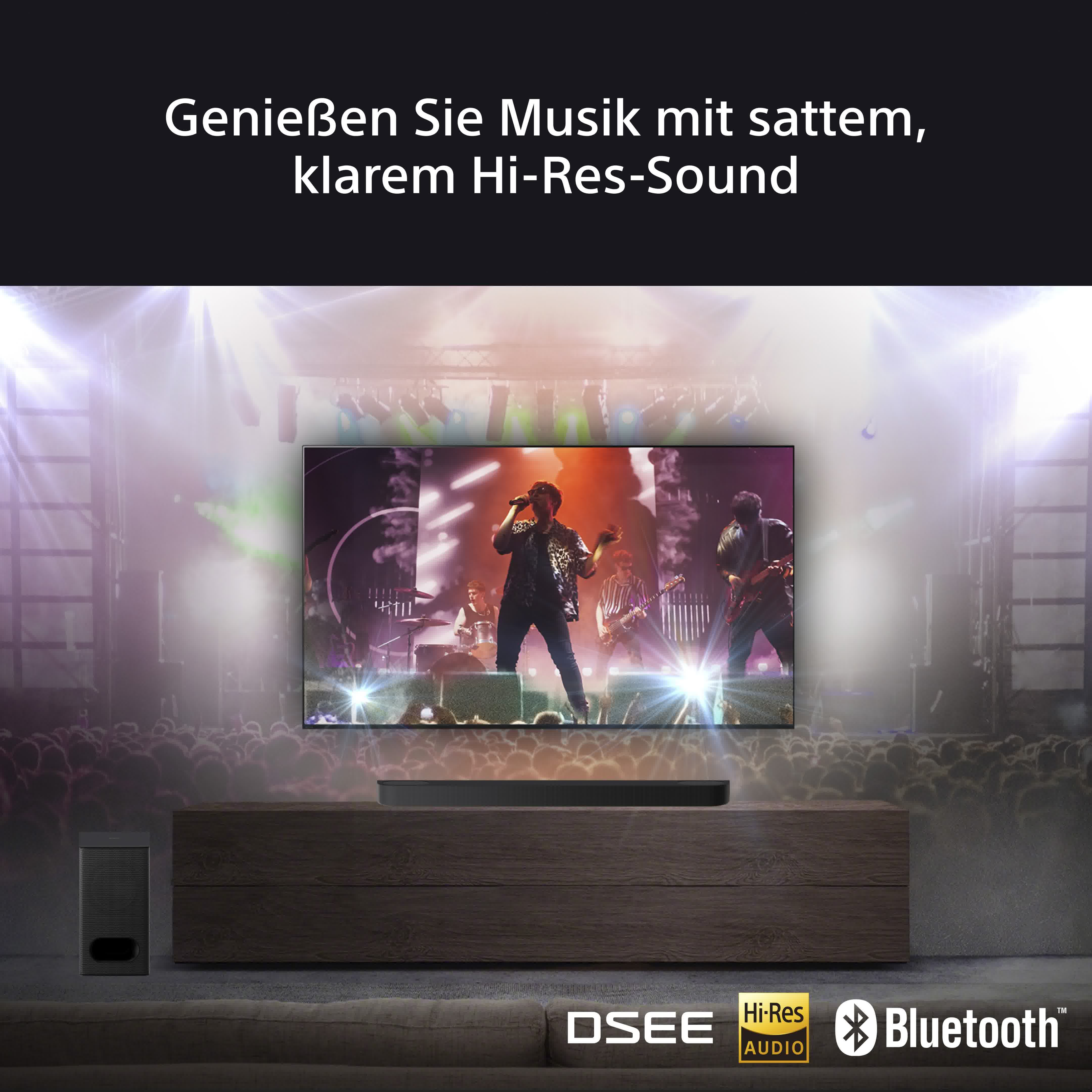Ein Fernsehbildschirm mit einer Konzertbühne, einer Soundbar und einem Subwoofer auf einem Holzständer.