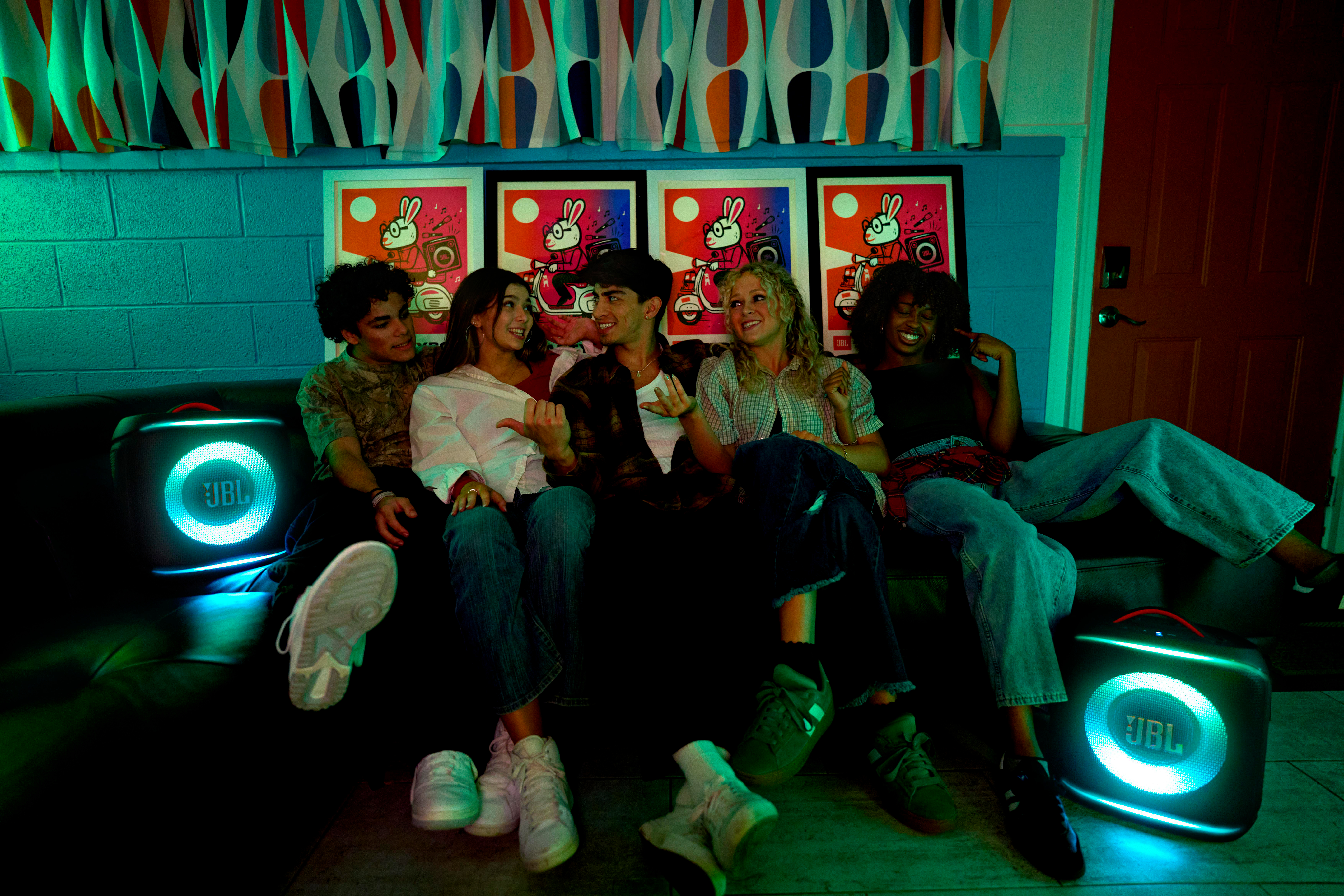 Gruppe von Freunden sitzt auf einem Sofa mit Lautsprechern.