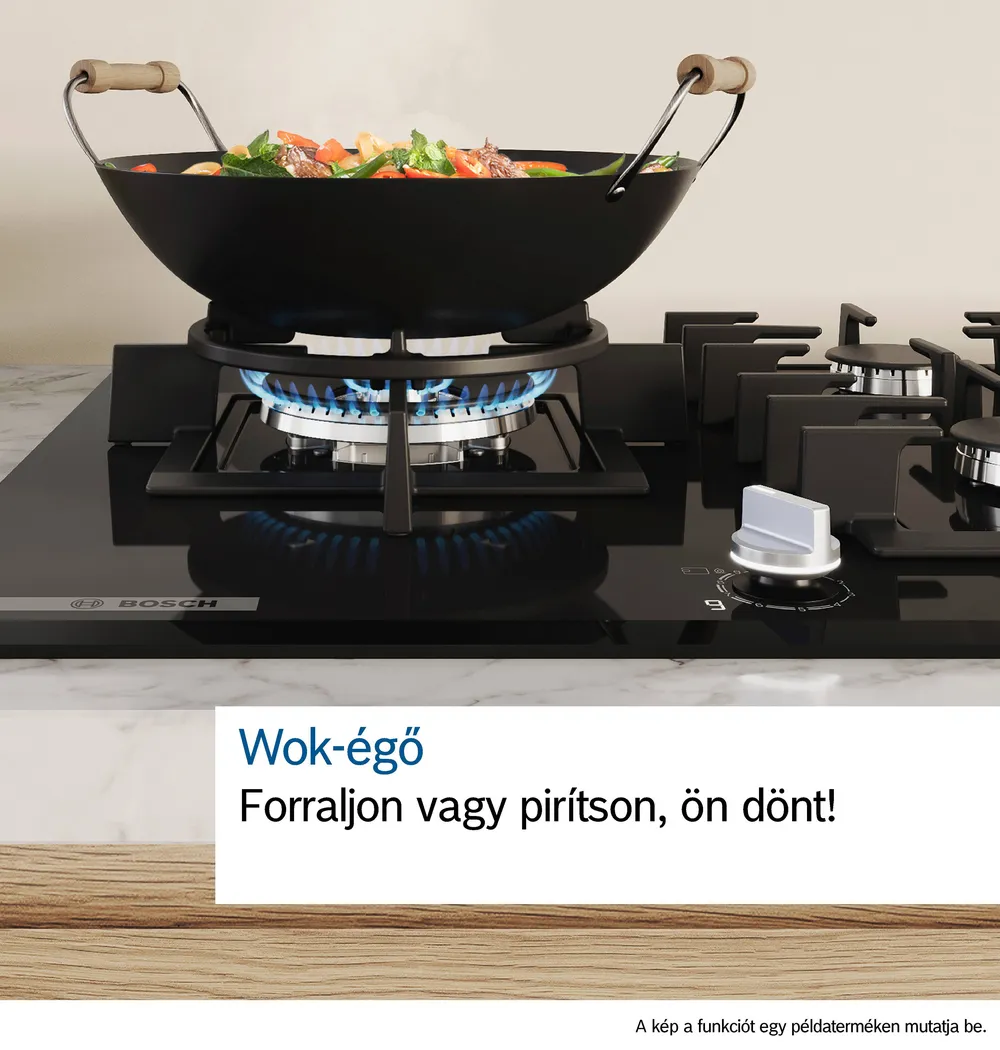 Fekete wok a gáztűzhelyen étellel benne. A tűzhely fekete-fehér.