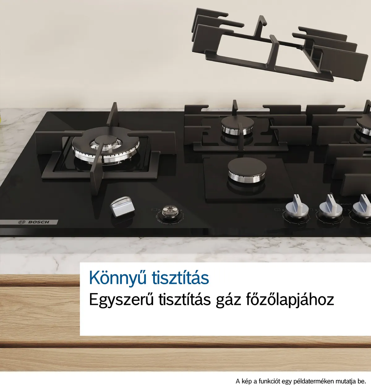 Gáztűzhely eltávolított égő alkatrészekkel. A tűzhely fekete, fehér pulttal.