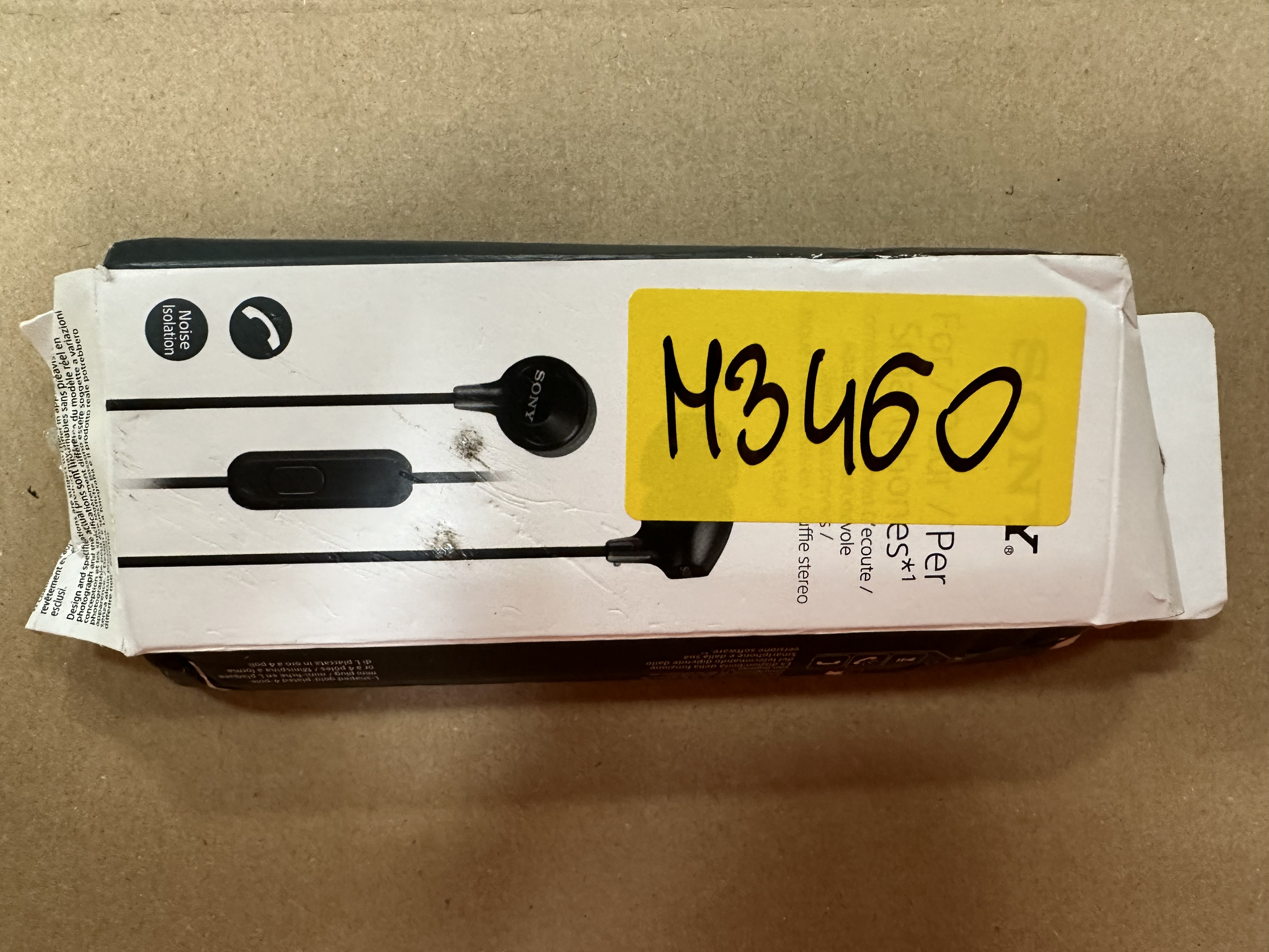 Pudełko słuchawek z żółtą naklejką i nadrukowanym tekstem.