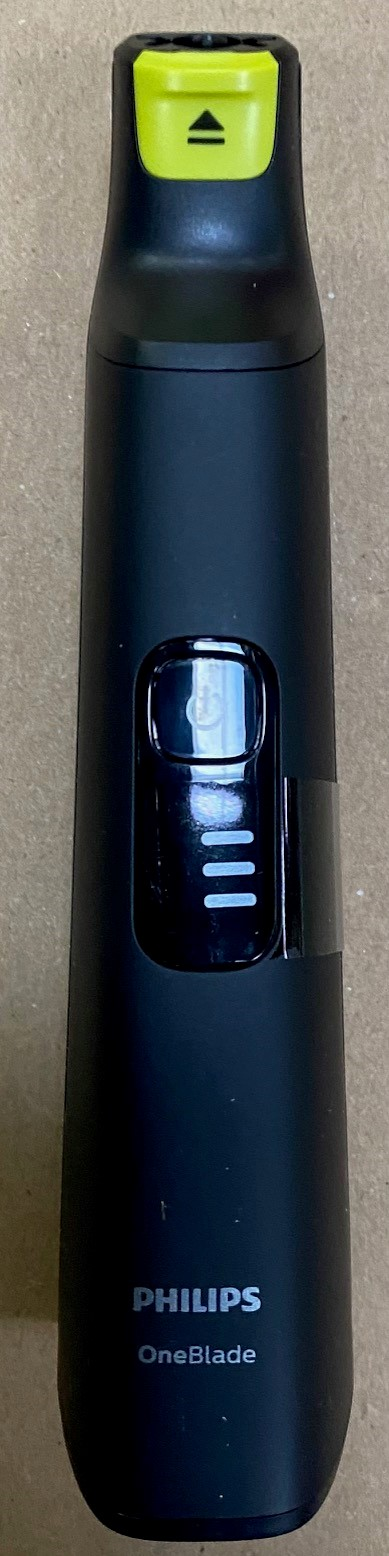 Czarna i zielona golarka elektryczna Philips OneBlade na jasnobrązowej powierzchni. Pionowa.