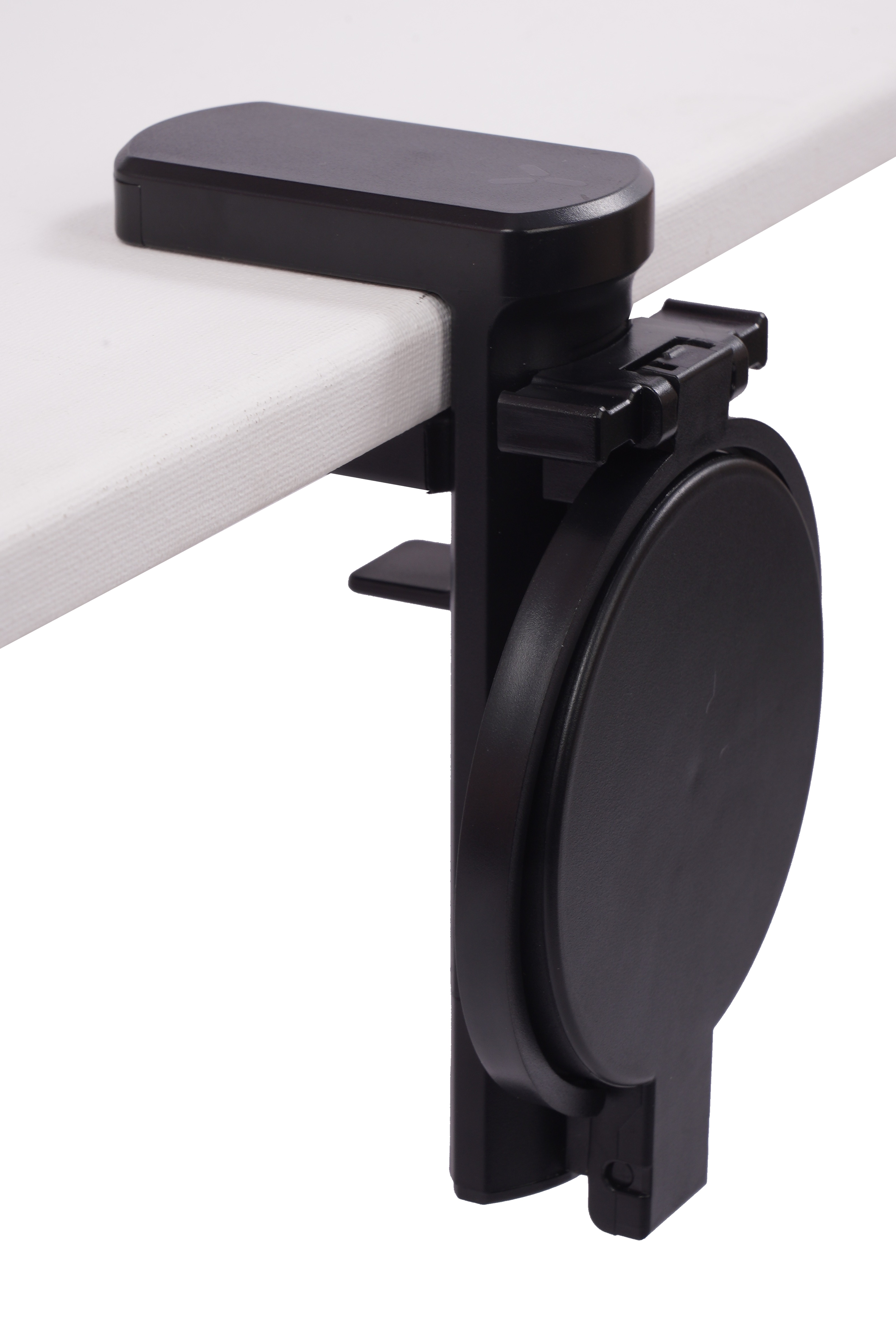 Schwarze Schreibtischklemme mit rundem Deckel, an einem weißen Tisch befestigt.
