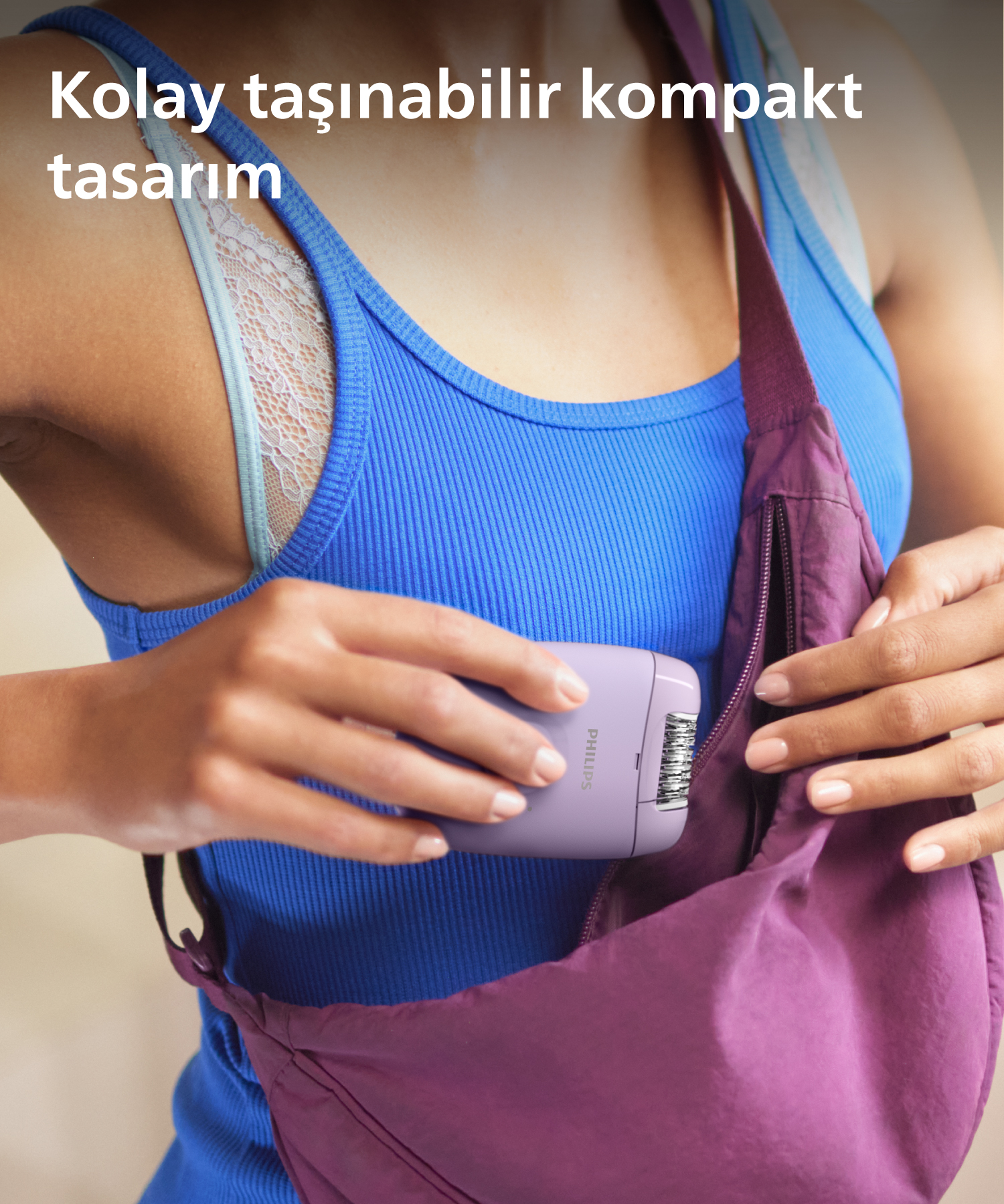 Kadın, mor bir tıraş makinesini bir çantaya koyuyor. Mavi bir üst giyiyor ve açık tenli.