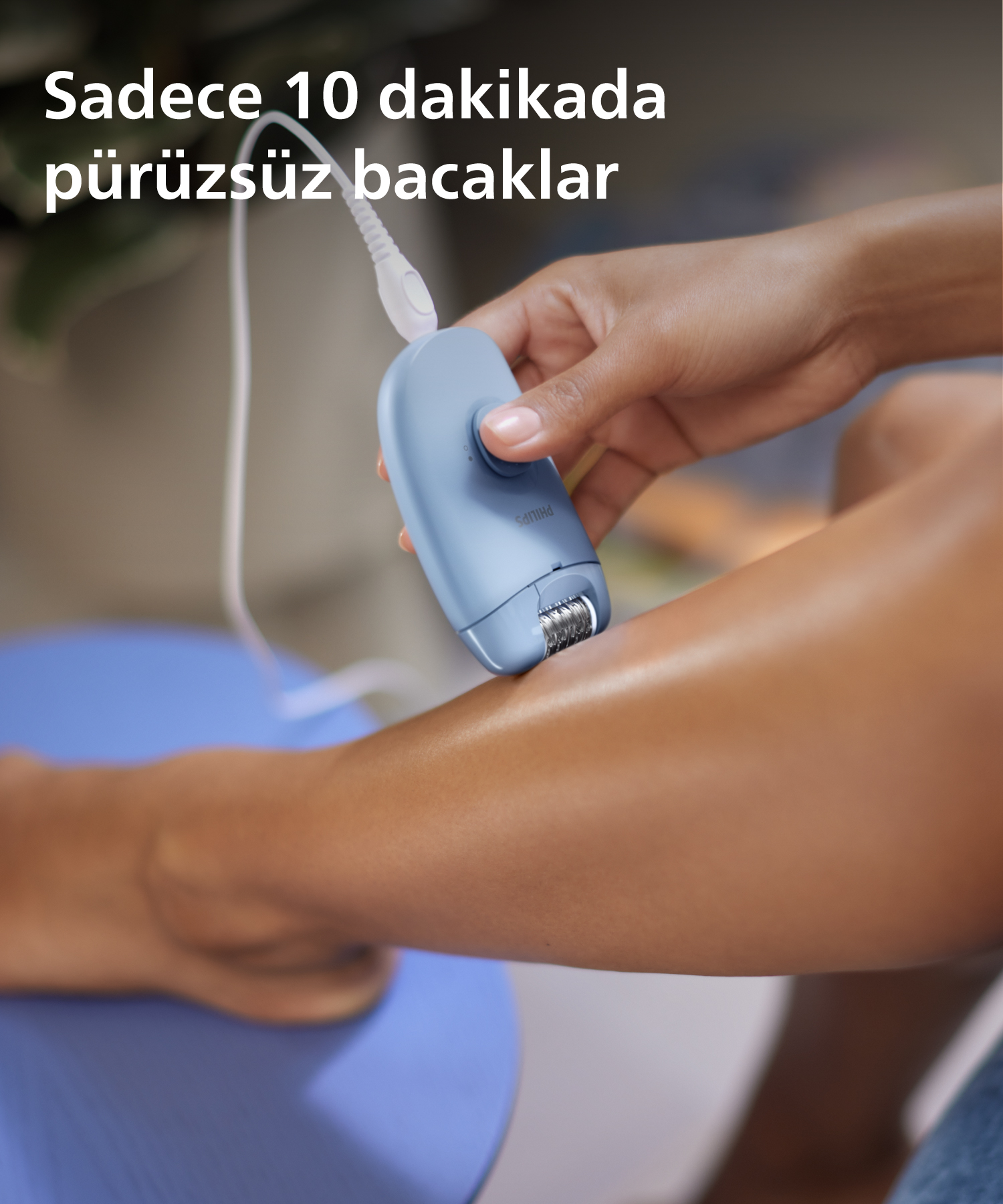 Bir kişi bacağında mavi bir epilatör kullanıyor. Bacak pürüzsüz.