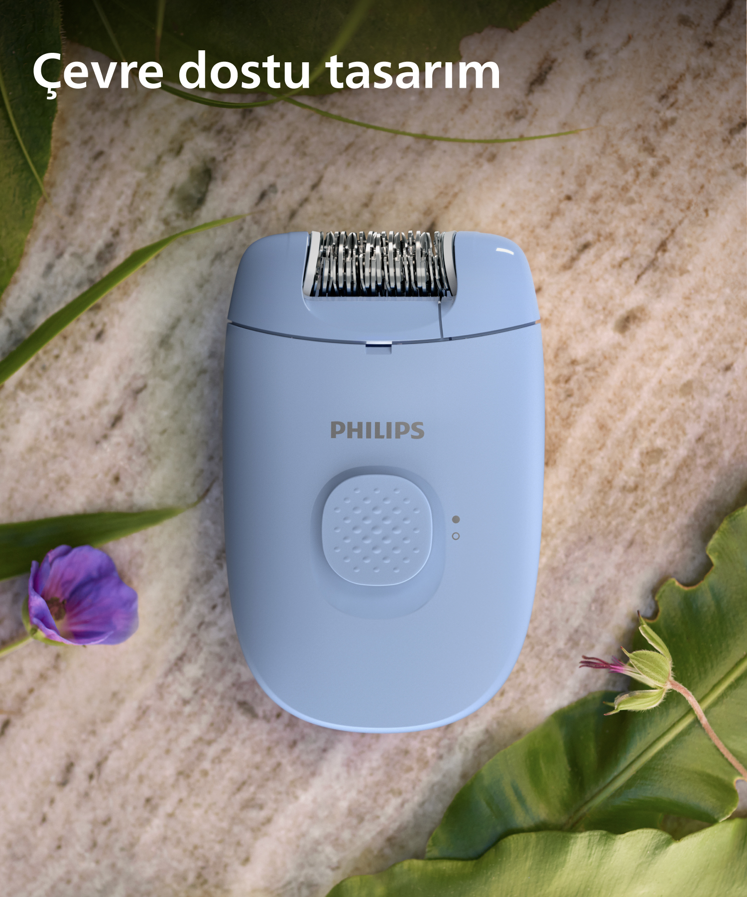 Mavi bir Philips epilatör, bir düğme ile. Yapraklar ve mor bir çiçek görülebilir.