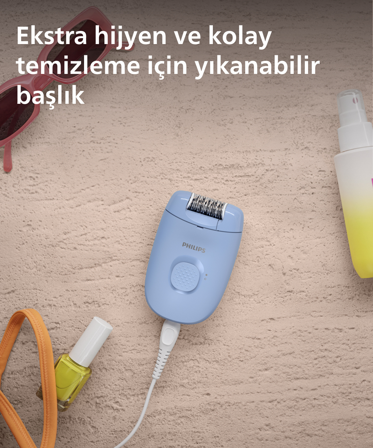 Kumlu yüzeyde aksesuarlarla mavi epilatör.