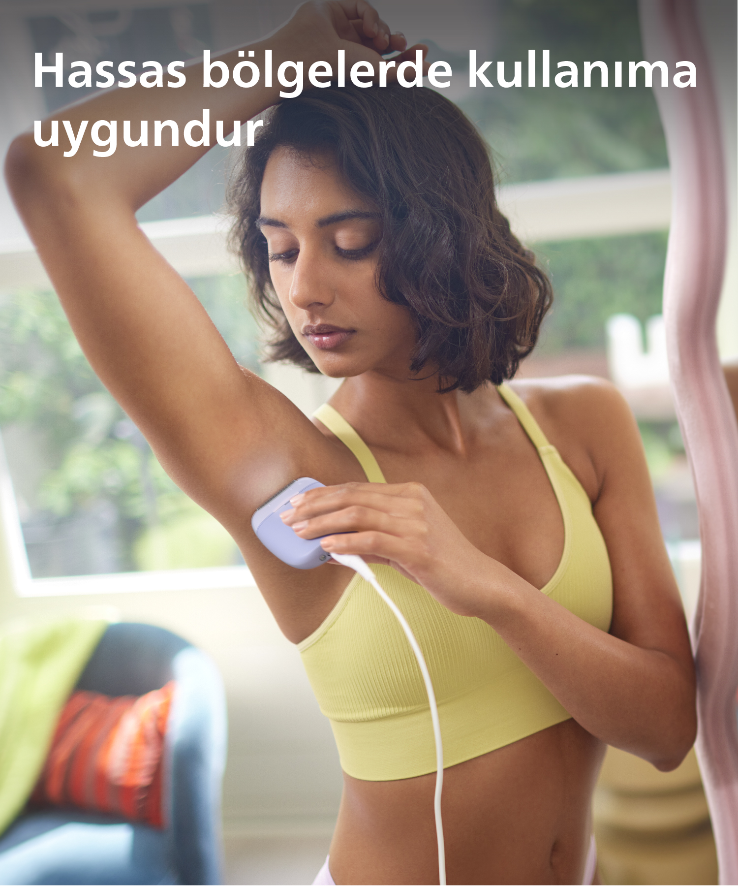 Kadın koltuk altında bir epilasyon cihazı kullanıyor.