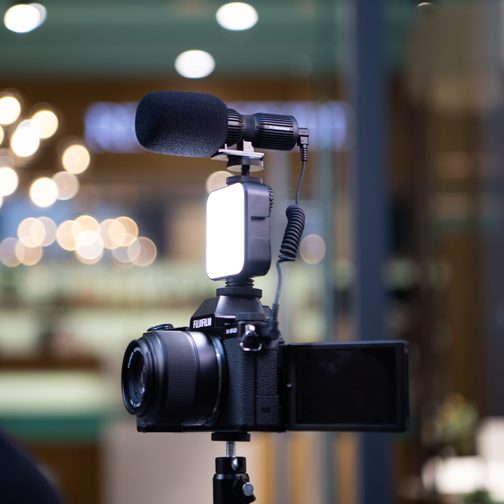 Mikrofon ve ışık ile kamera. Bulanık arka plan ve ışıklar. Kamera bir tripod üzerinde.