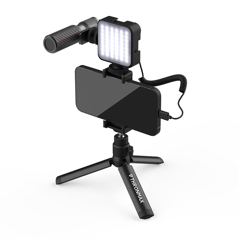 Bir tripod üzerine monte edilmiş mikrofon ve ışıklı akıllı telefon. Tamamen siyah kurulum.