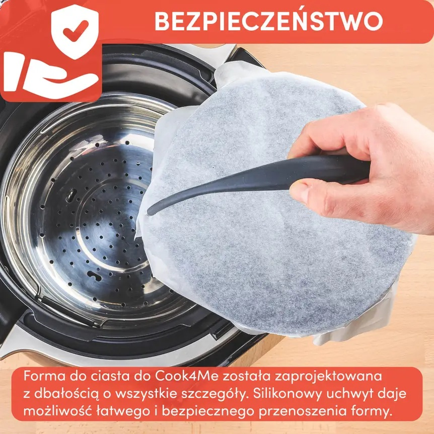 Dłoń trzymająca silikonowy uchwyt formy do ciasta Cook4Me z papierem.