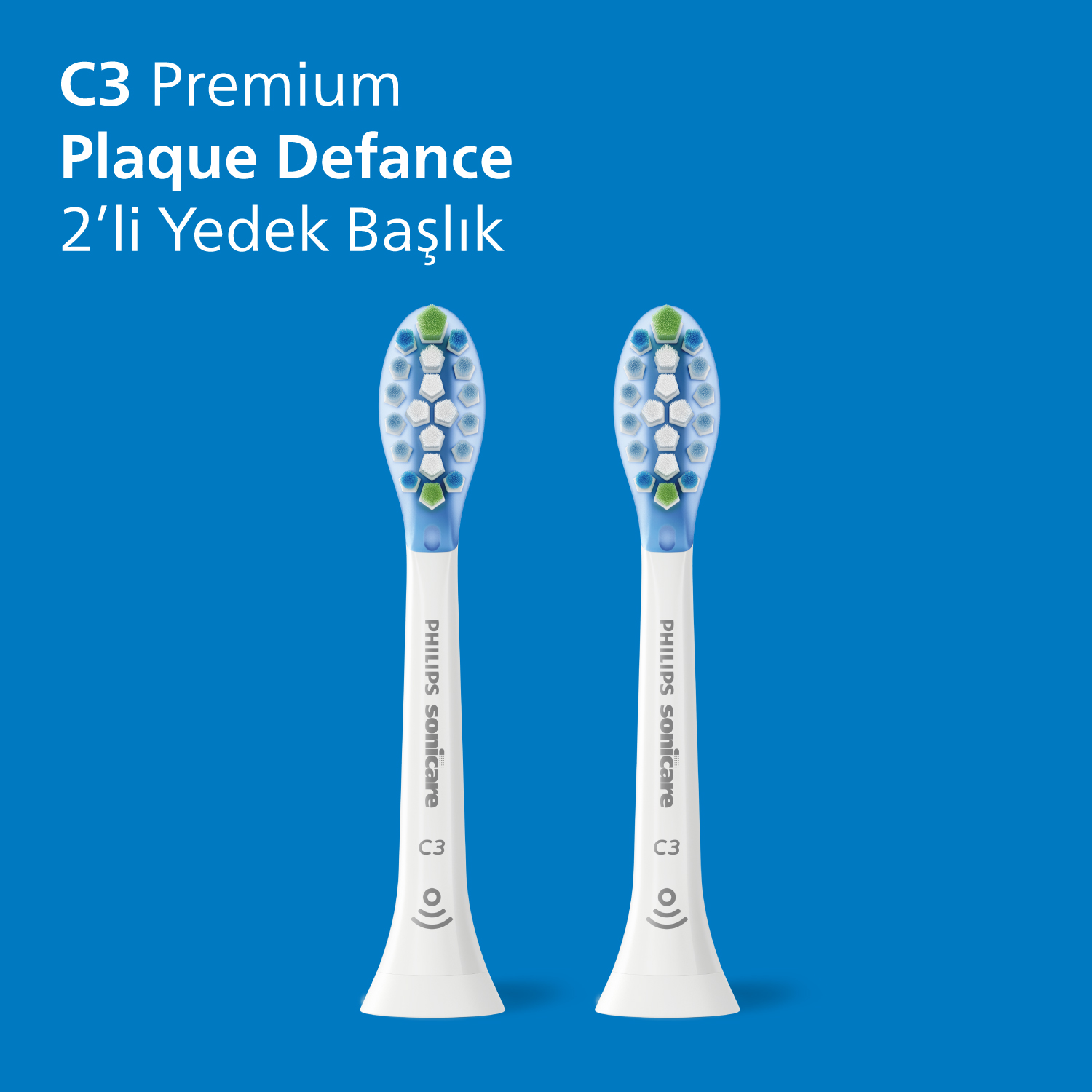 Mavi ve yeşil kıllara sahip iki beyaz diş fırçası başlığı, mavi bir arka plan üzerinde.