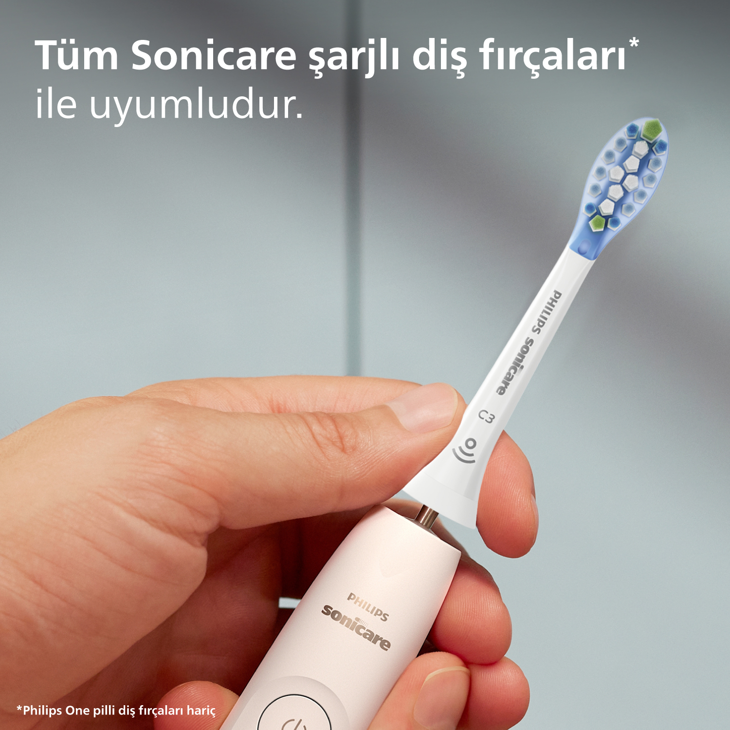Bir el Philips Sonicare diş fırçası tutuyor. Fırça, mavi ve yeşil kıllarla beyazdır.