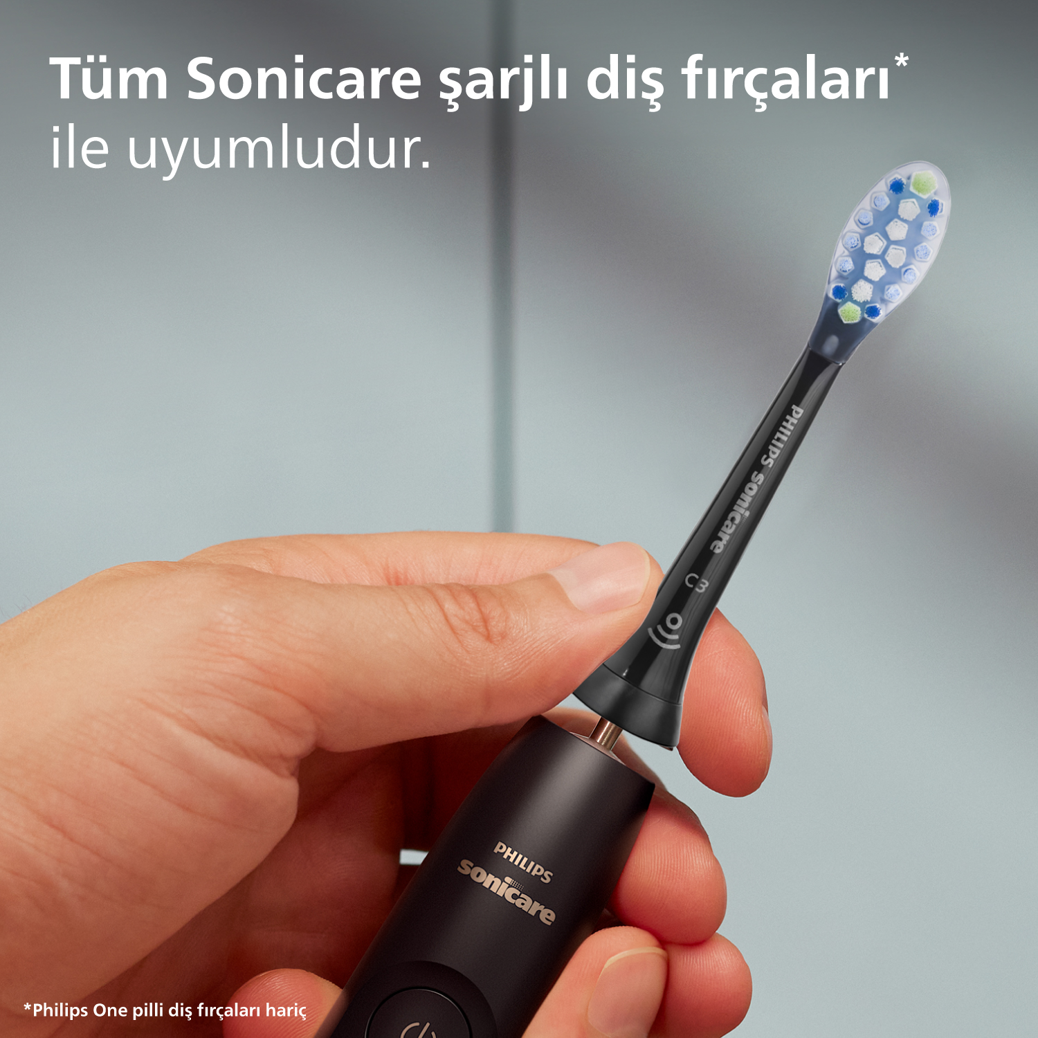 El, siyah ve gümüş renkli elektrikli bir diş fırçasını tutuyor. Mavi ve yeşil kıllar.