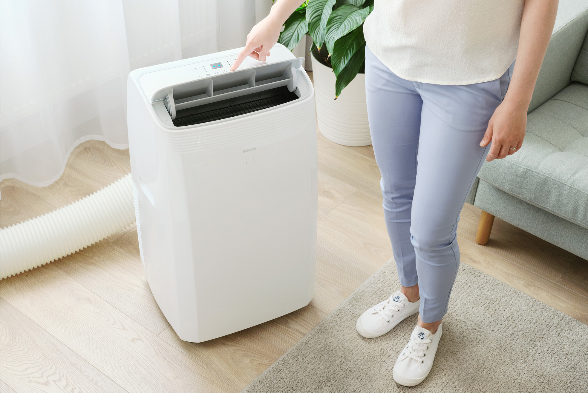 Kobieta w pokoju z klimatyzacją, dotykająca panelu sterowania.