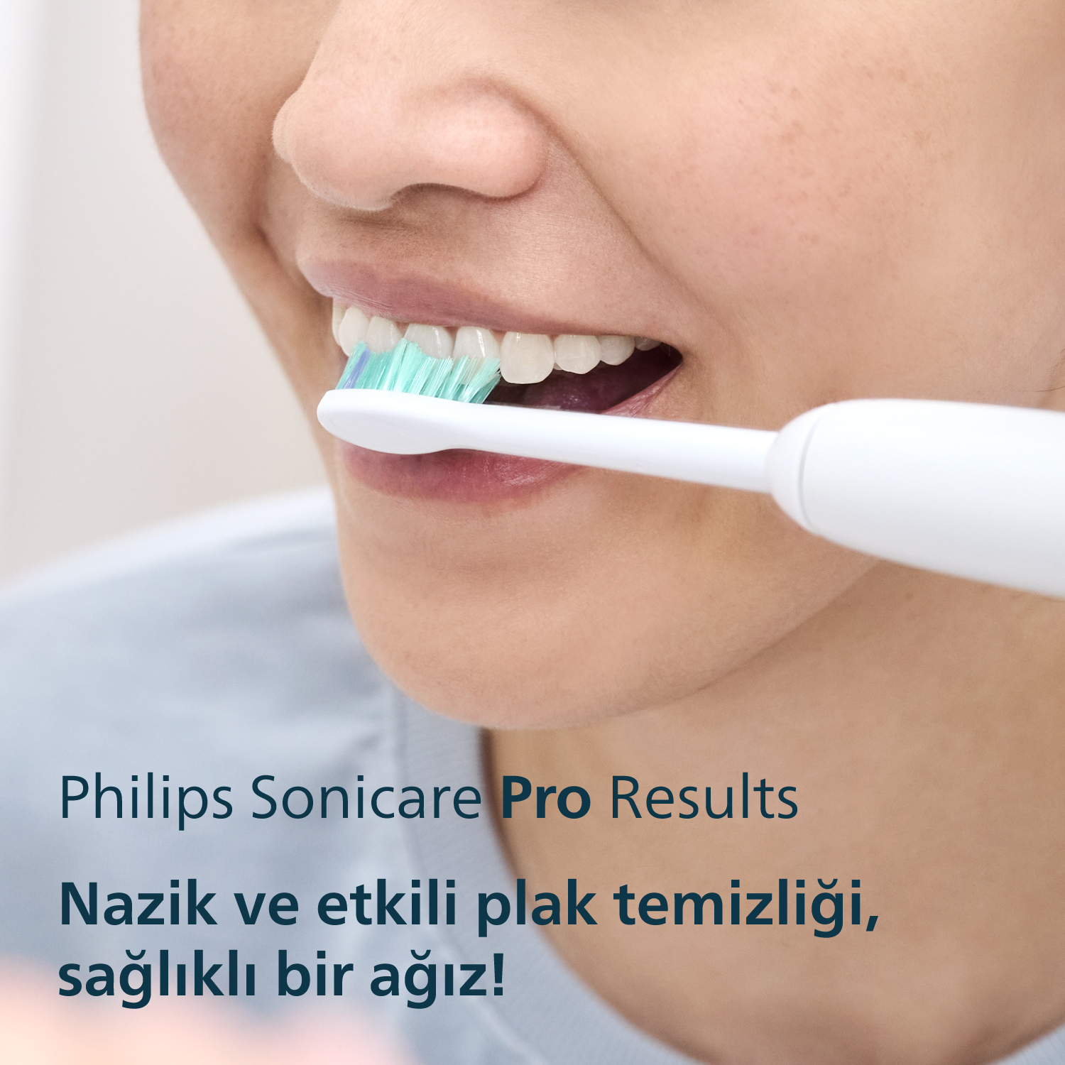 Bir kadın elektrikli diş fırçasıyla dişlerini fırçalıyor, yakın çekim.