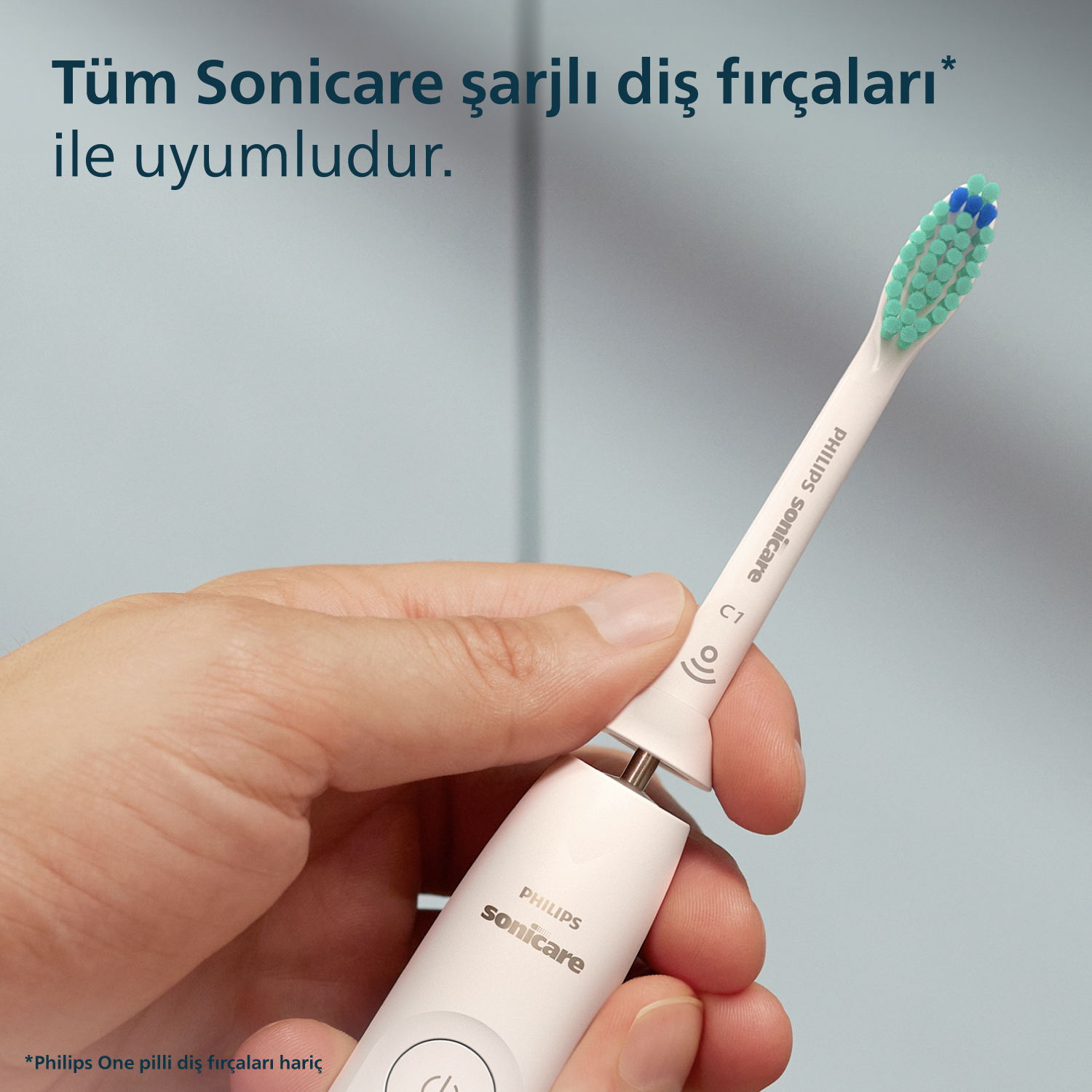 Mavi ve yeşil kıllı bir başlığı olan beyaz bir elektrikli diş fırçasını tutan bir el.