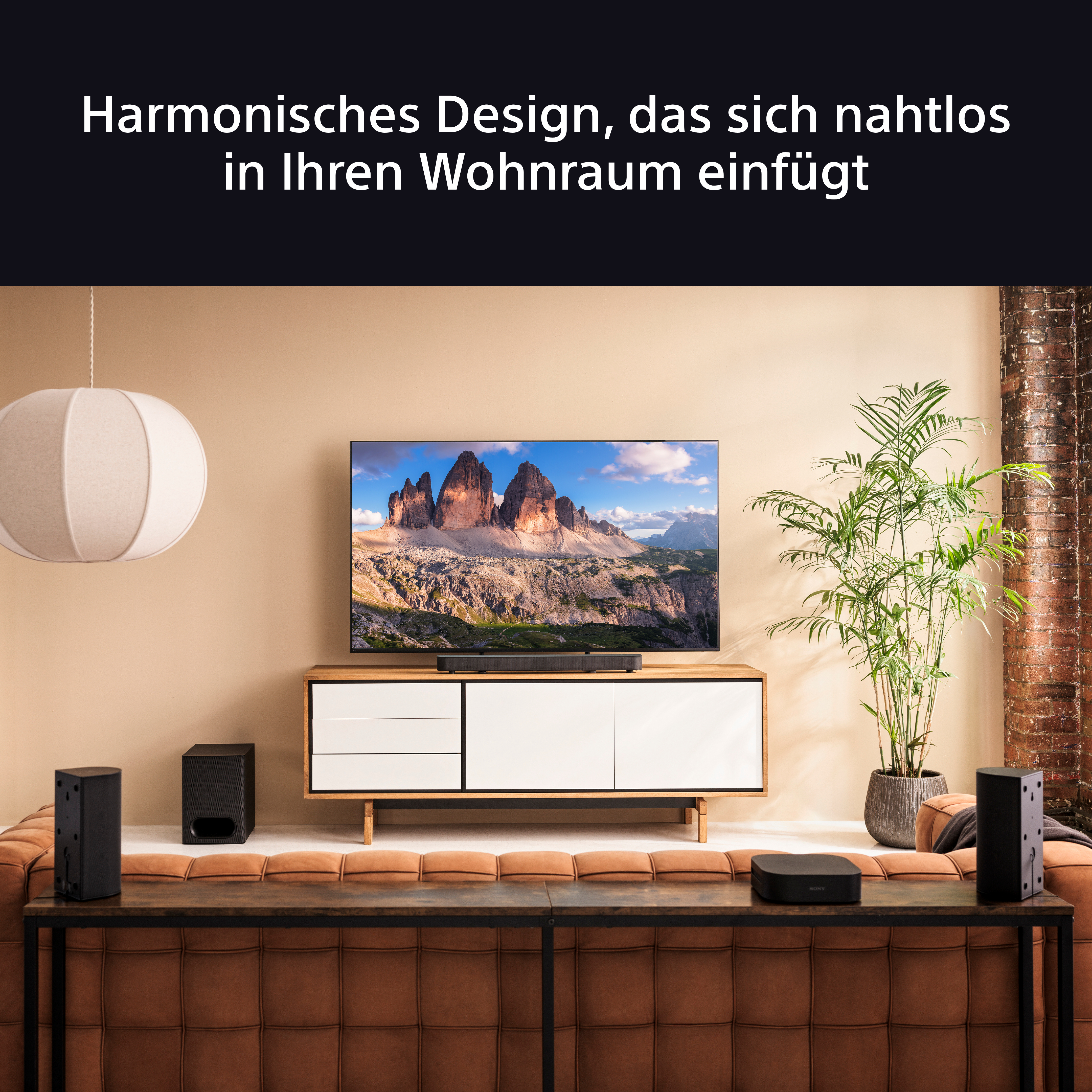 Wohnzimmer mit Fernseher, Soundbar, Lautsprechern und brauner Couch und Teppich.