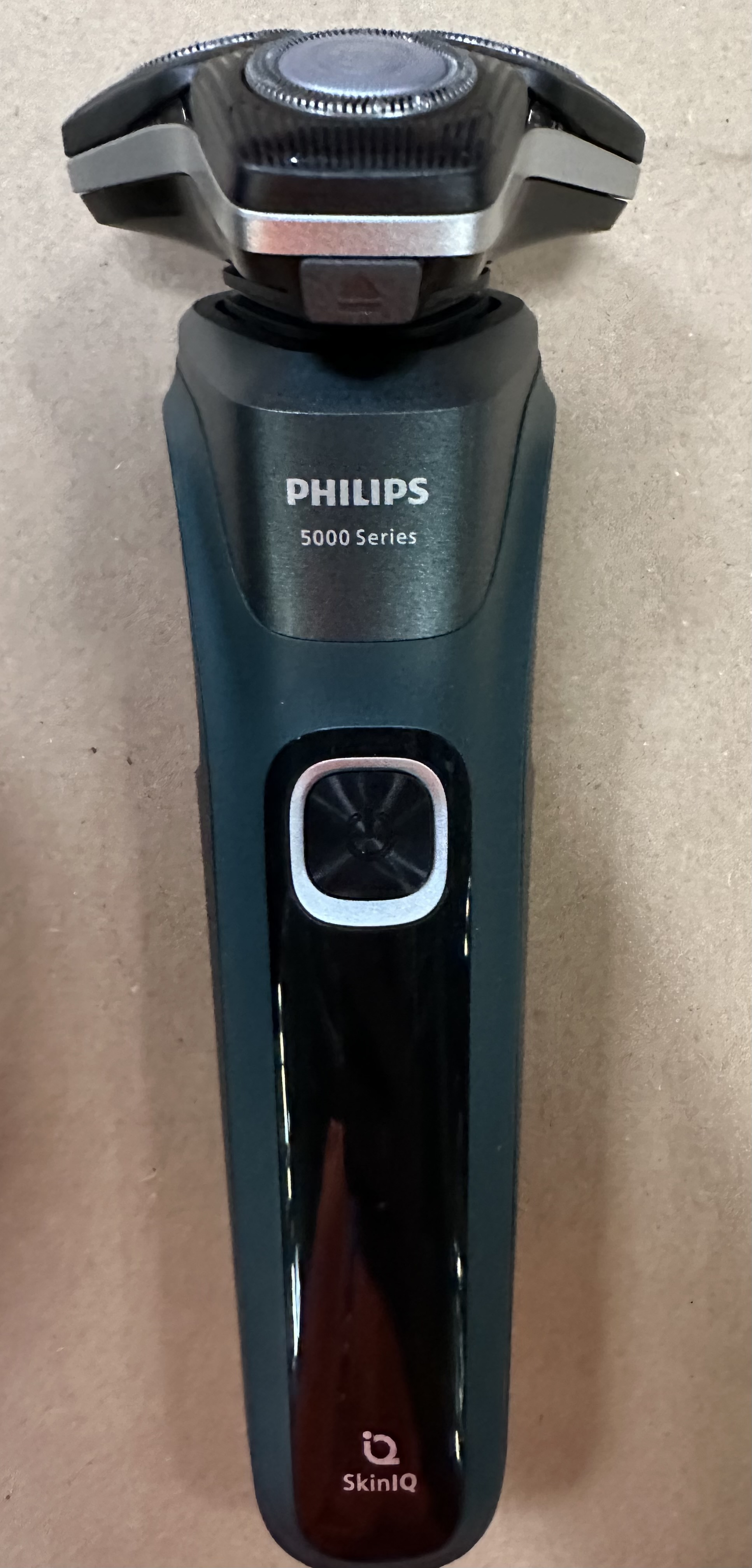 Elektryczna golarka Philips serii 5000, turkusowa i czarna, na drewnianej powierzchni.