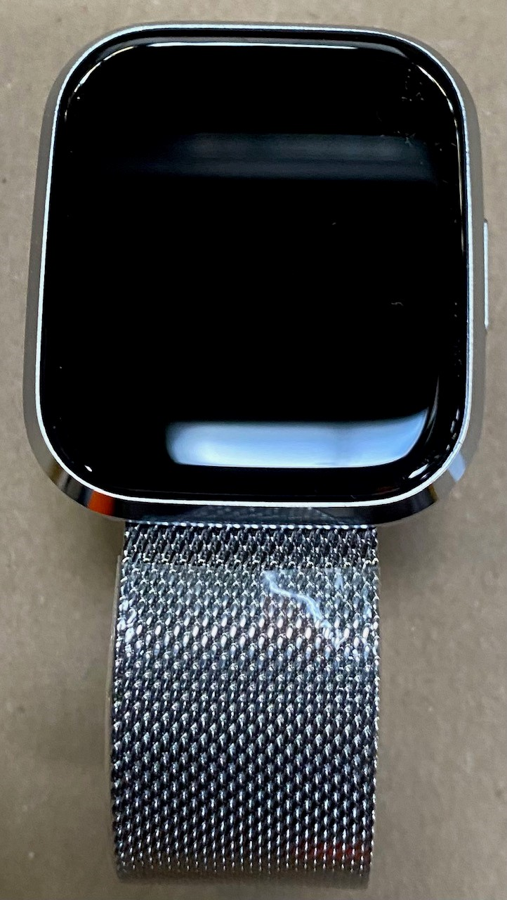 Srebrny smartwatch z czarnym ekranem i srebrnym paskiem z siatki.