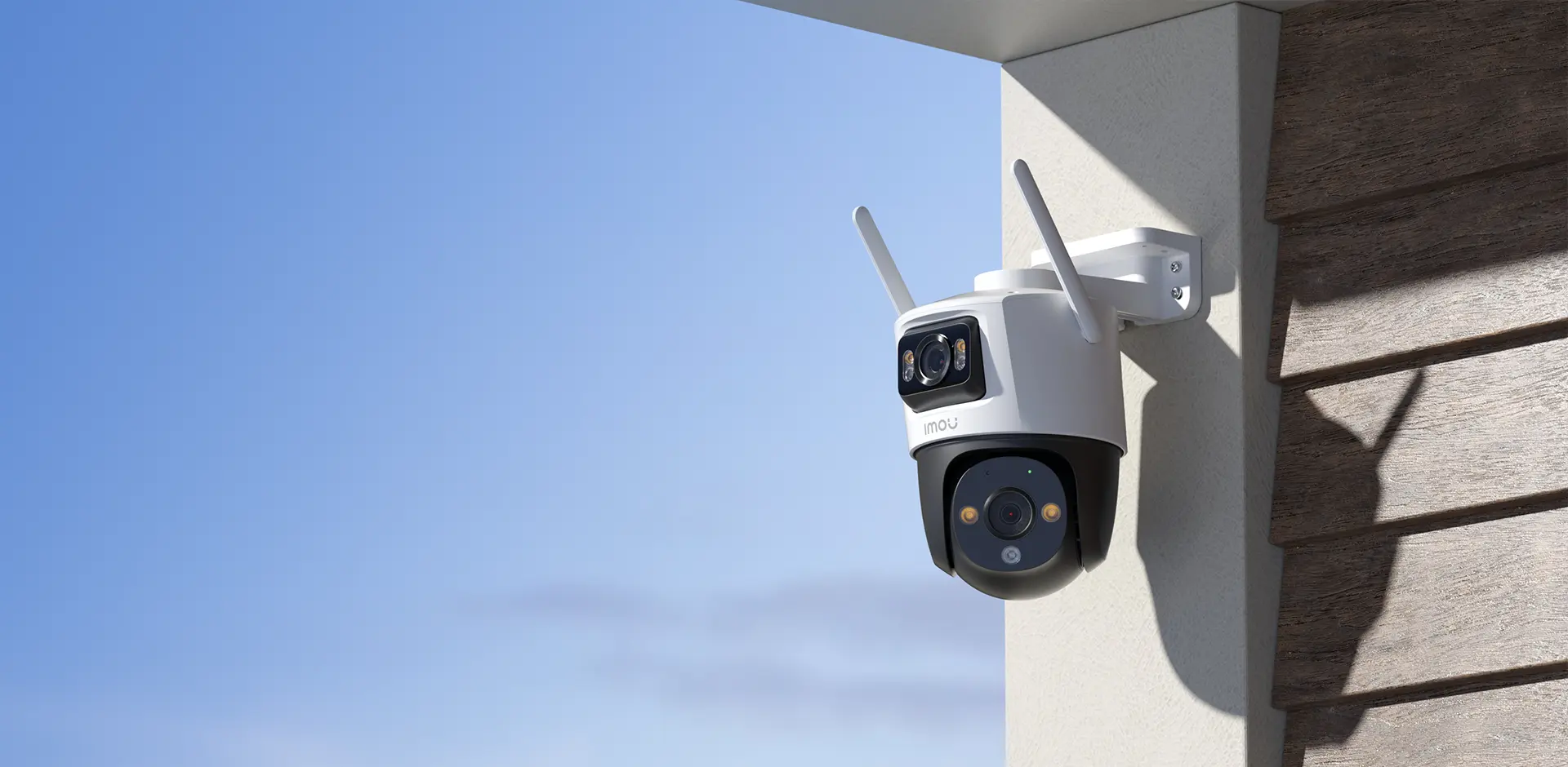 Zewnętrzna kamera bezpieczeństwa zamontowana na ścianie. Ma dwie anteny i czarno-biały korpus.