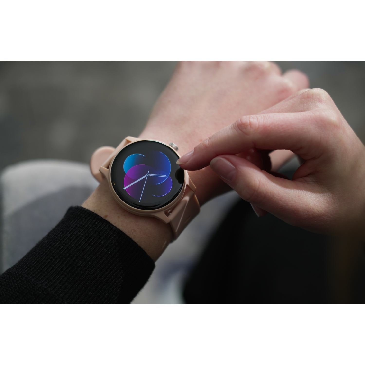 A person's hand touching a smartwatch displaying a colorful abstract design.