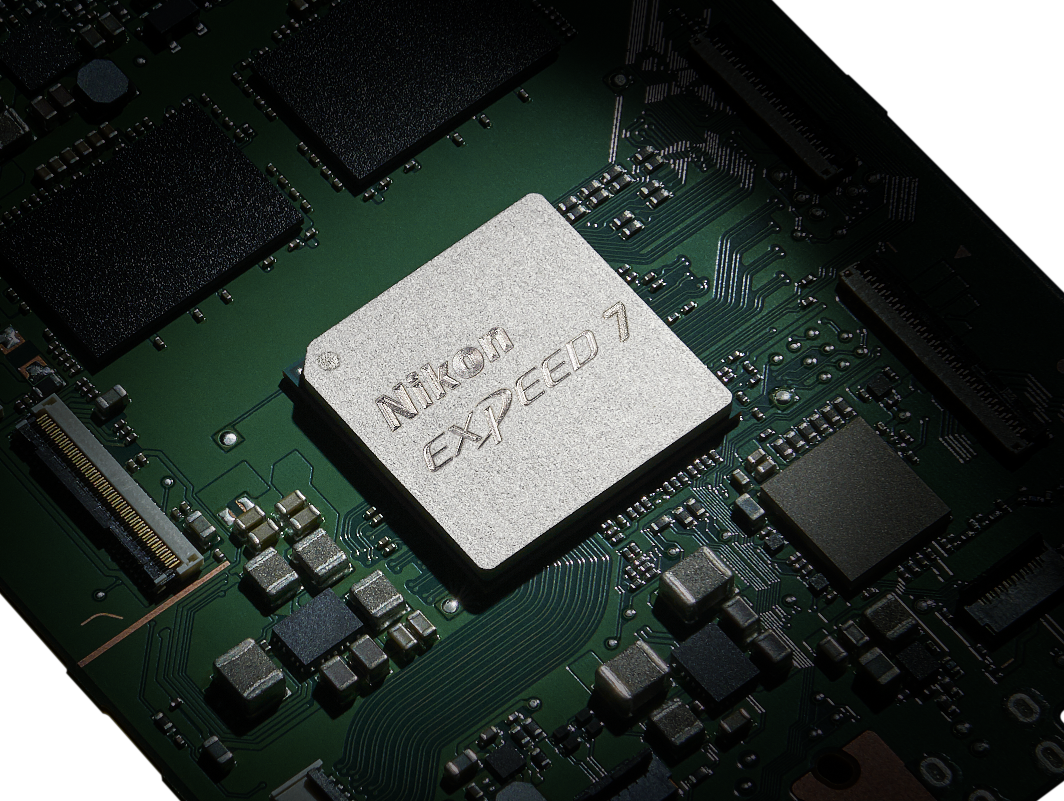 Gros plan d'une carte de circuit imprimé verte avec une puce argentée Nikon Expeed 7 au centre.