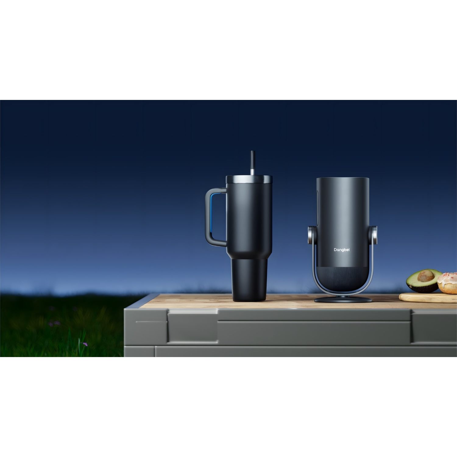 Two black tumblers on a table, one with a handle. Avocado and a donut are on the right. Green grass and blue sky background.
