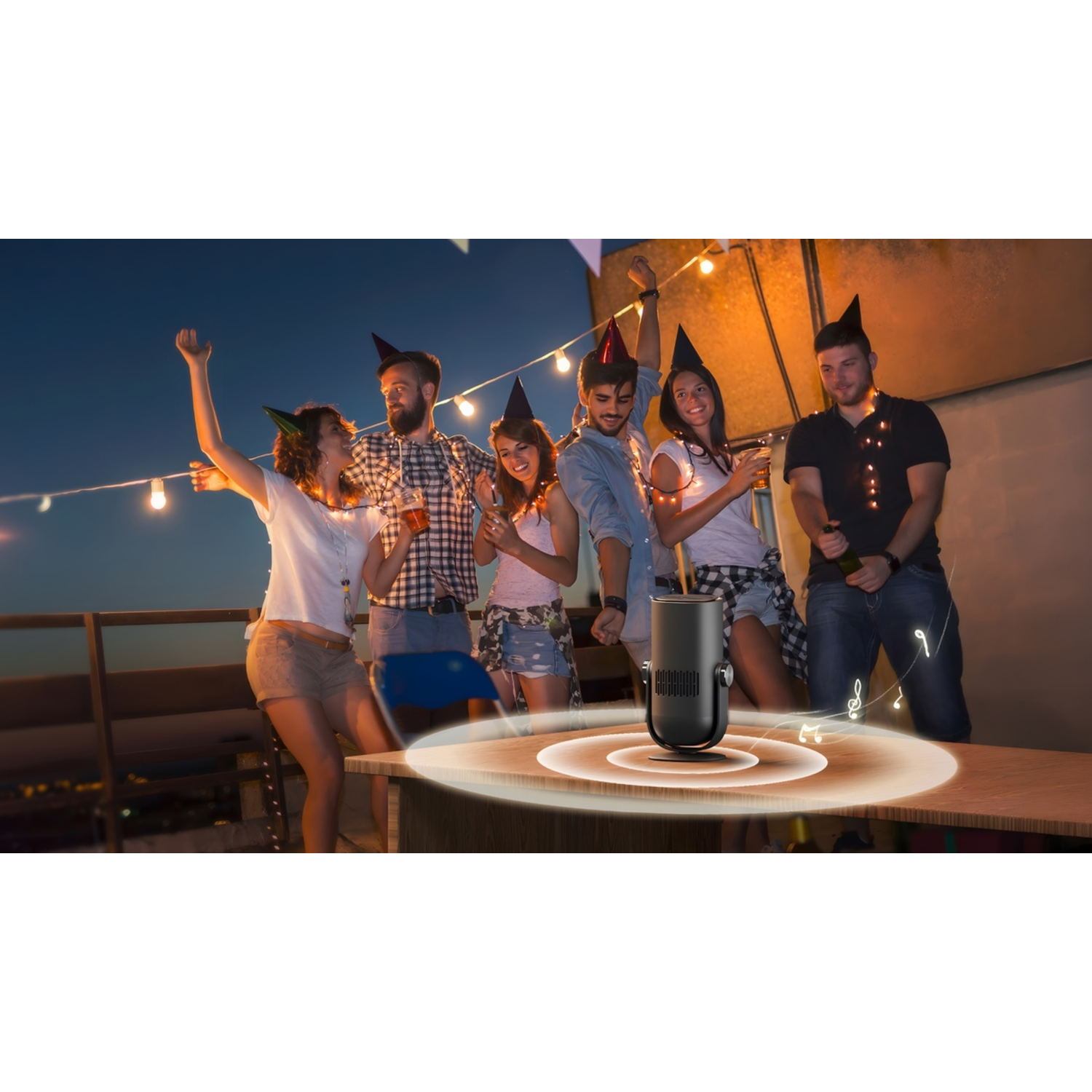 Group of friends celebrating on a rooftop. A speaker is on the table, and people are dancing and drinking.
