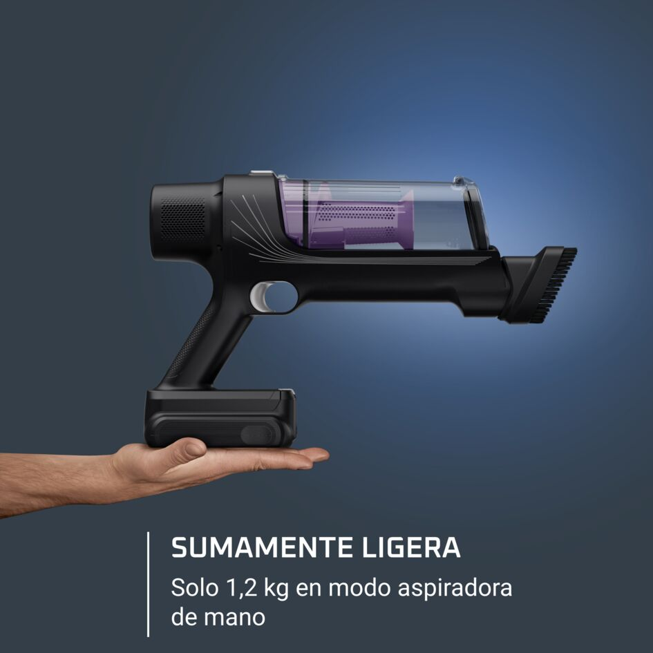 Una aspiradora de mano negra sostenida por una mano. Tiene un contenedor transparente y el texto 'SUMAMENTE LIGERA'.