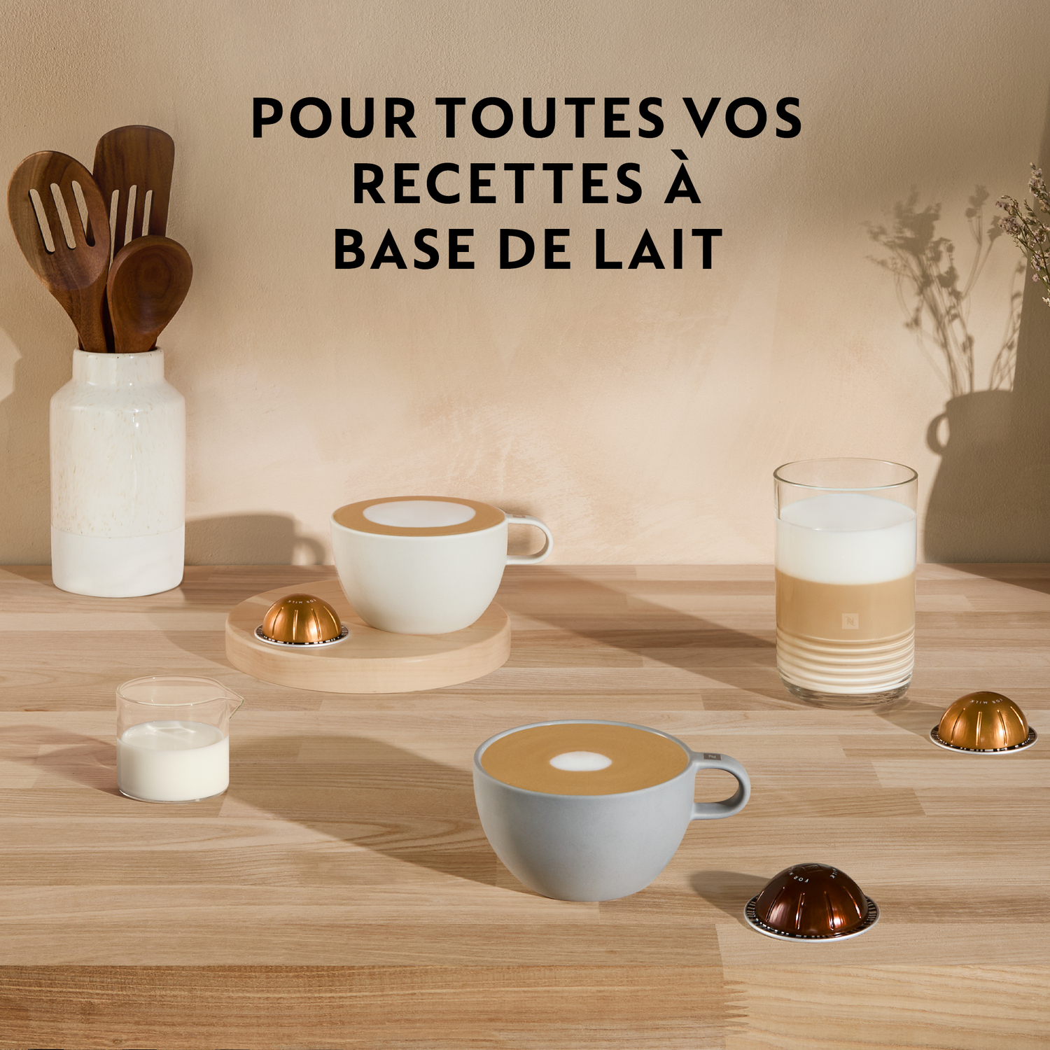 Tasses de café et de lait, avec dosettes et cuillères en bois sur une table.