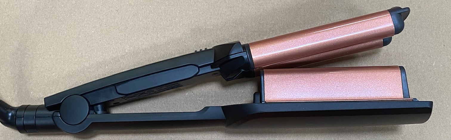 Karbowarka do włosów z płytkami w kolorze różowego złota, czarnymi uchwytami i przewodem zasilającym.