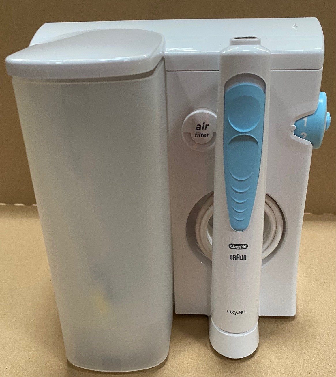 Oral-B OxyJet z białą podstawą, przezroczystym zbiornikiem na wodę i niebieskimi akcentami na uchwycie.